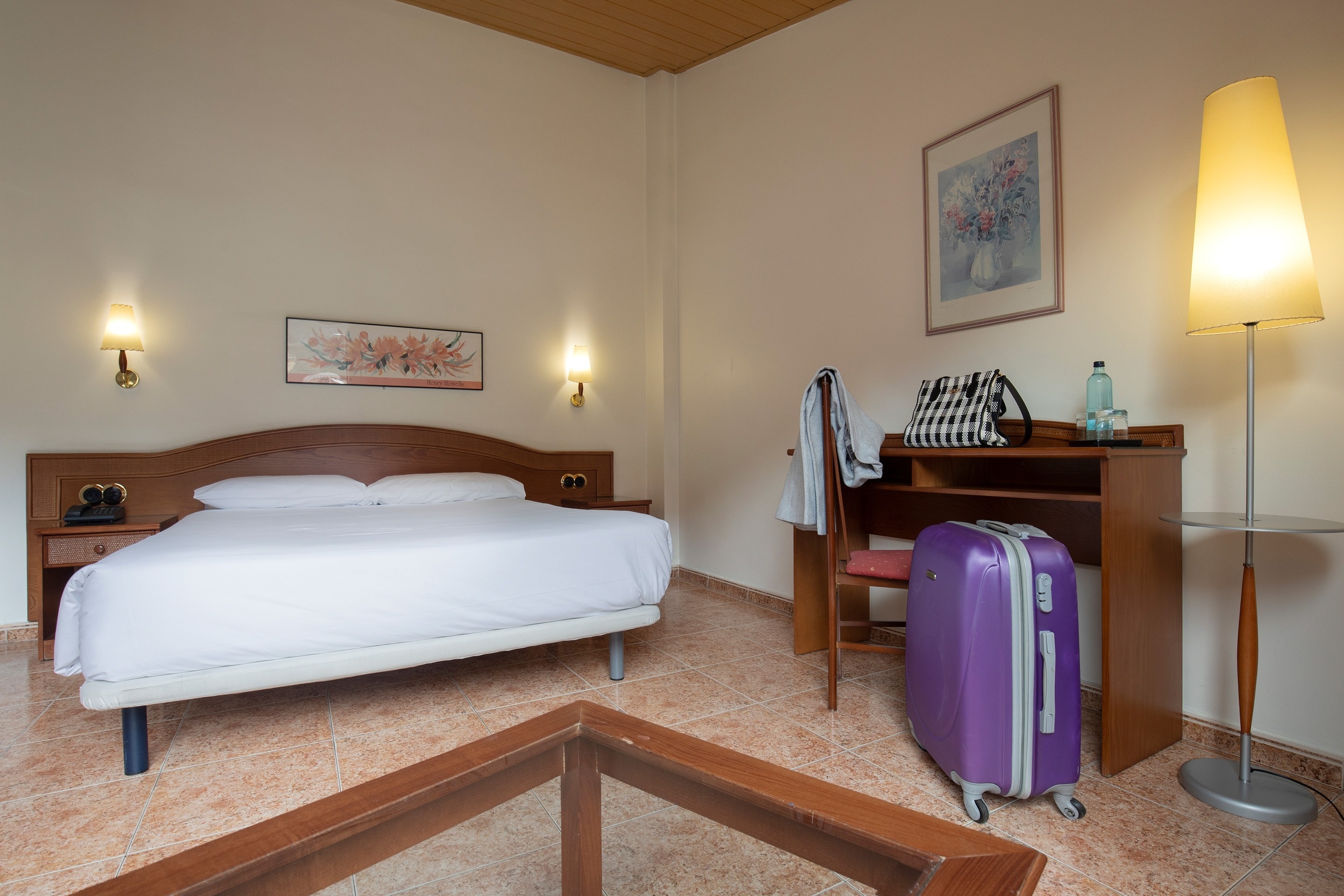a hotel room with a bed and a purple suitcase
