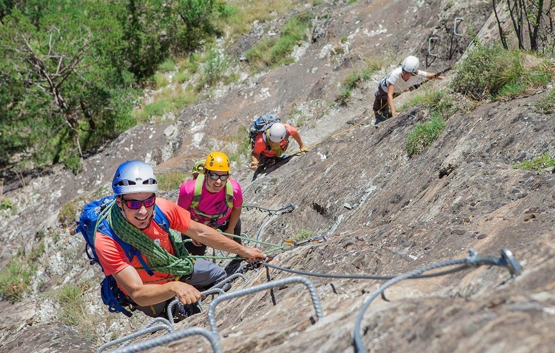 un grup de persones escalant una roca amb corda