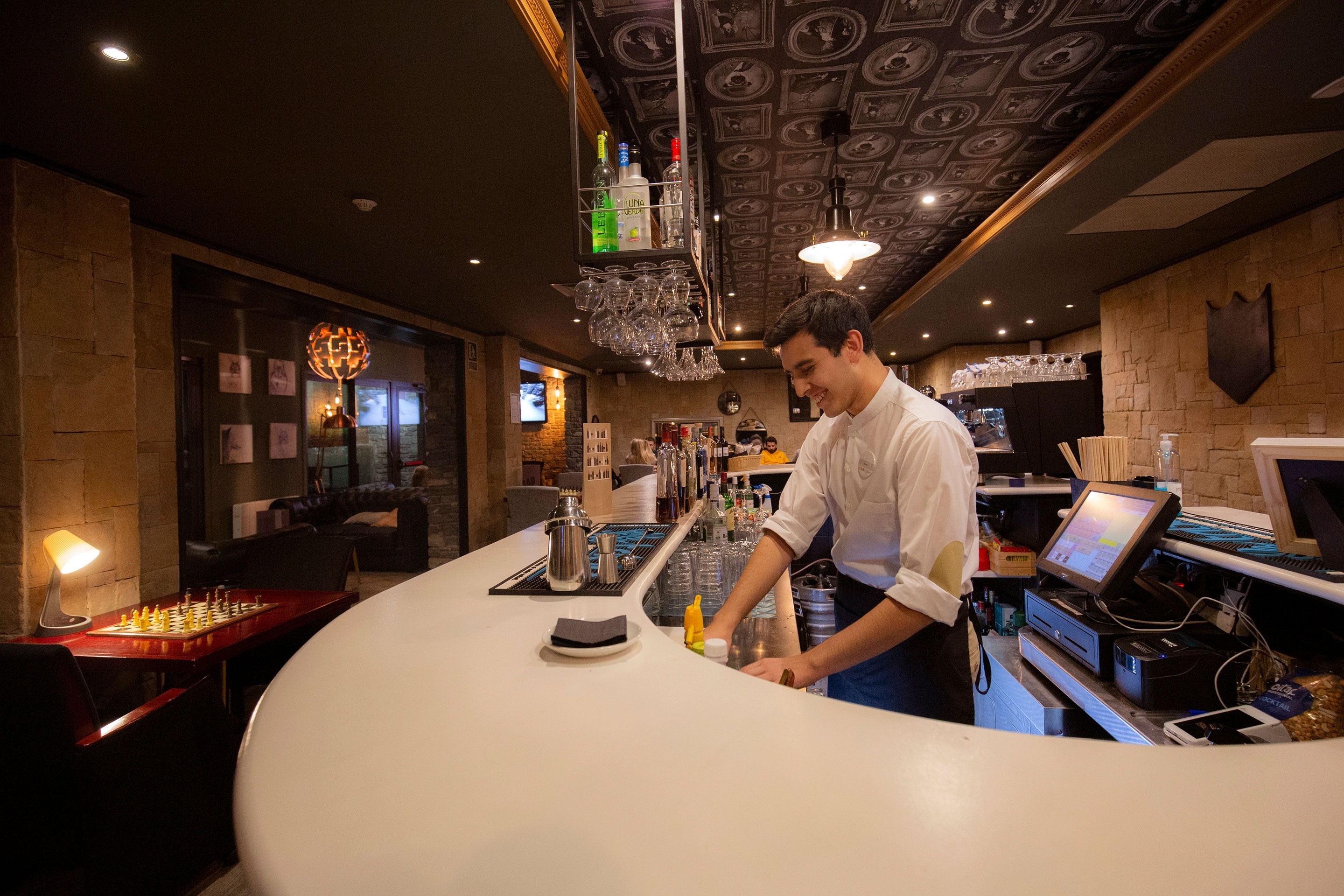 un barman travaille à un comptoir avec des bouteilles de spiritueux à l' arrière