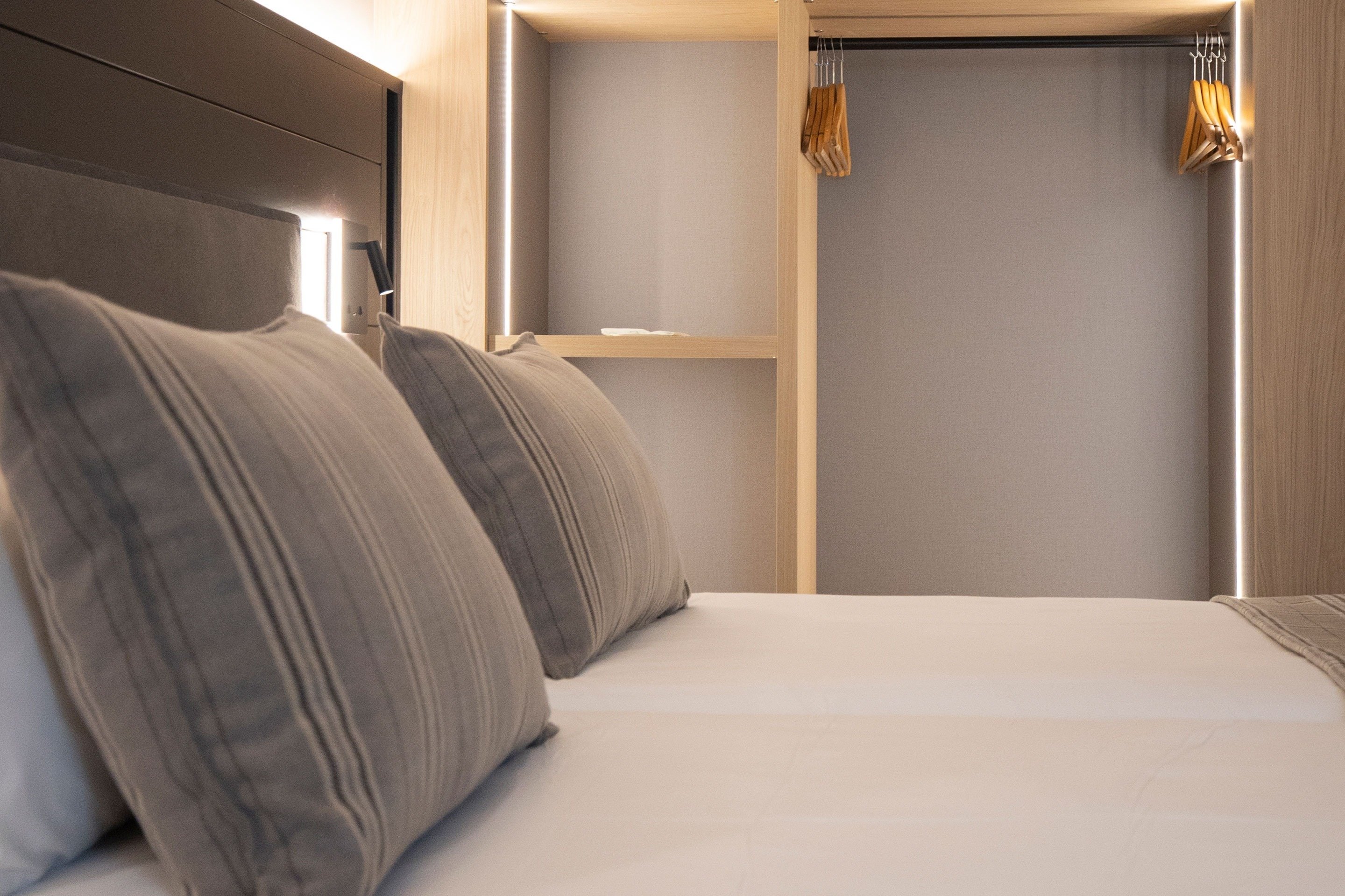 a bedroom with pillows and a closet with clothes hanging on it