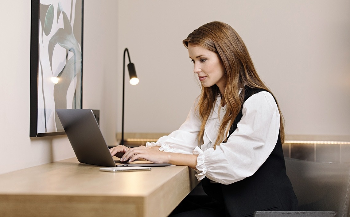 a woman sits in a white chair using a laptop