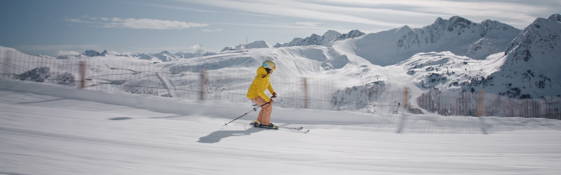 a person in a yellow jacket is skiing down a snowy slope