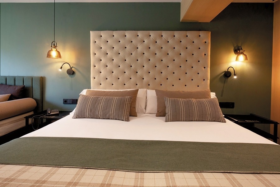 a bed with a headboard and pillows in a hotel room