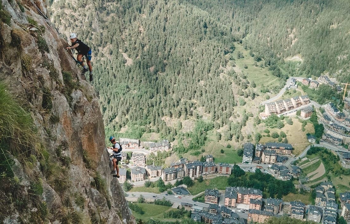 a man climbs a mountain with a city in the background