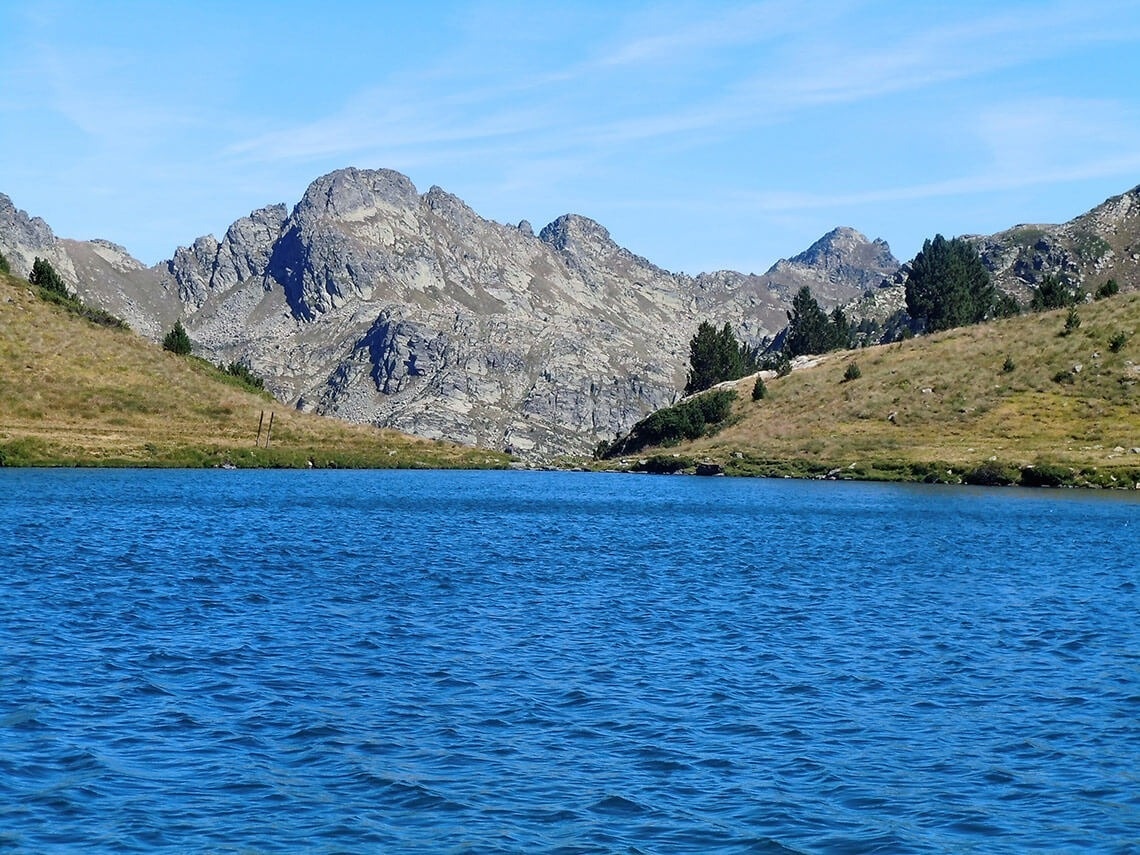un lago con montañas en el fondo y un cielo azul