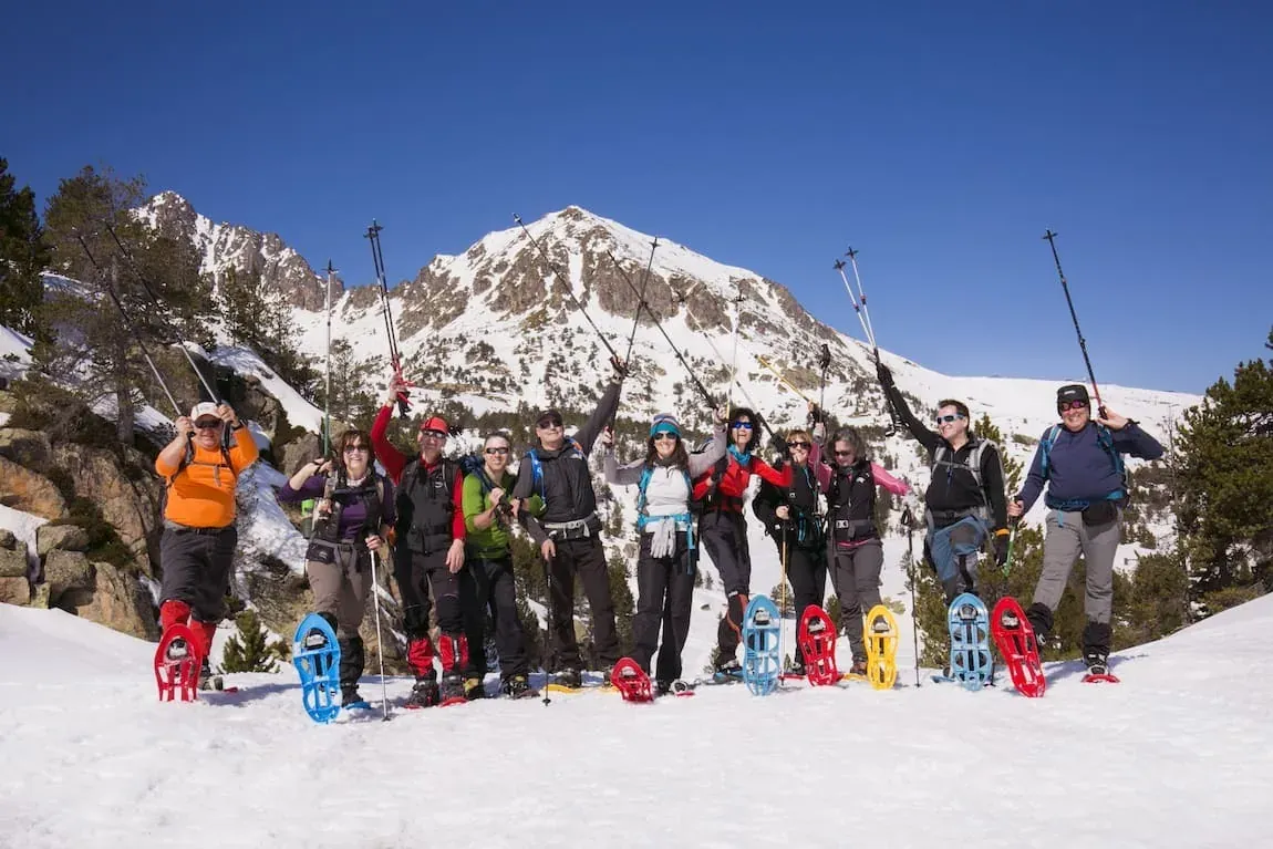 Group snowshoeing at NEXTA: Corporativa with snowy mountains.