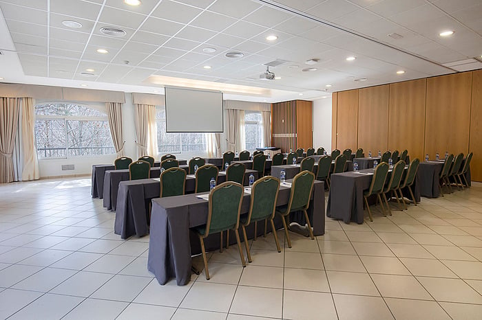Empty classroom chairs with gold trim at tables, ready for guests in a hotel meeting room NEXTA: Corporativa.