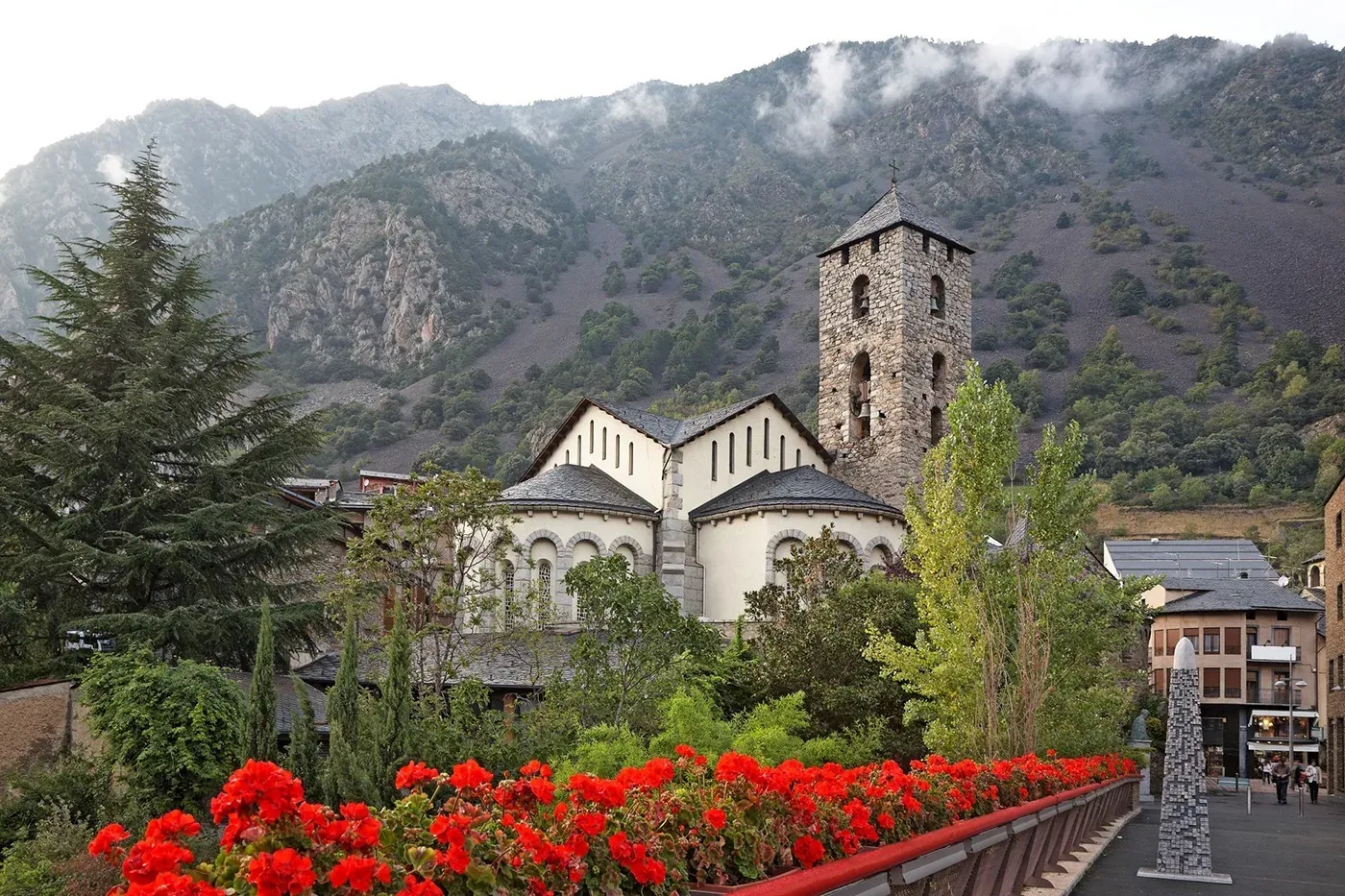 Église romane avec cloches et fleurs rouges, vue NEXTA: Corporativa.