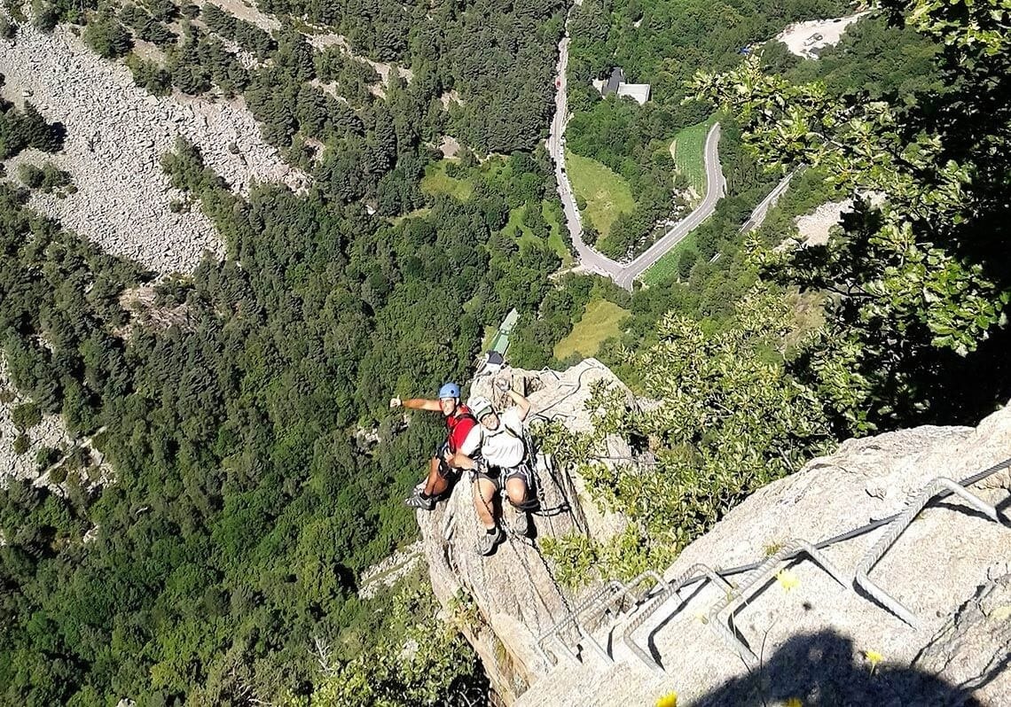 un hombre está escalando una roca en una montaña con una carretera en el fondo