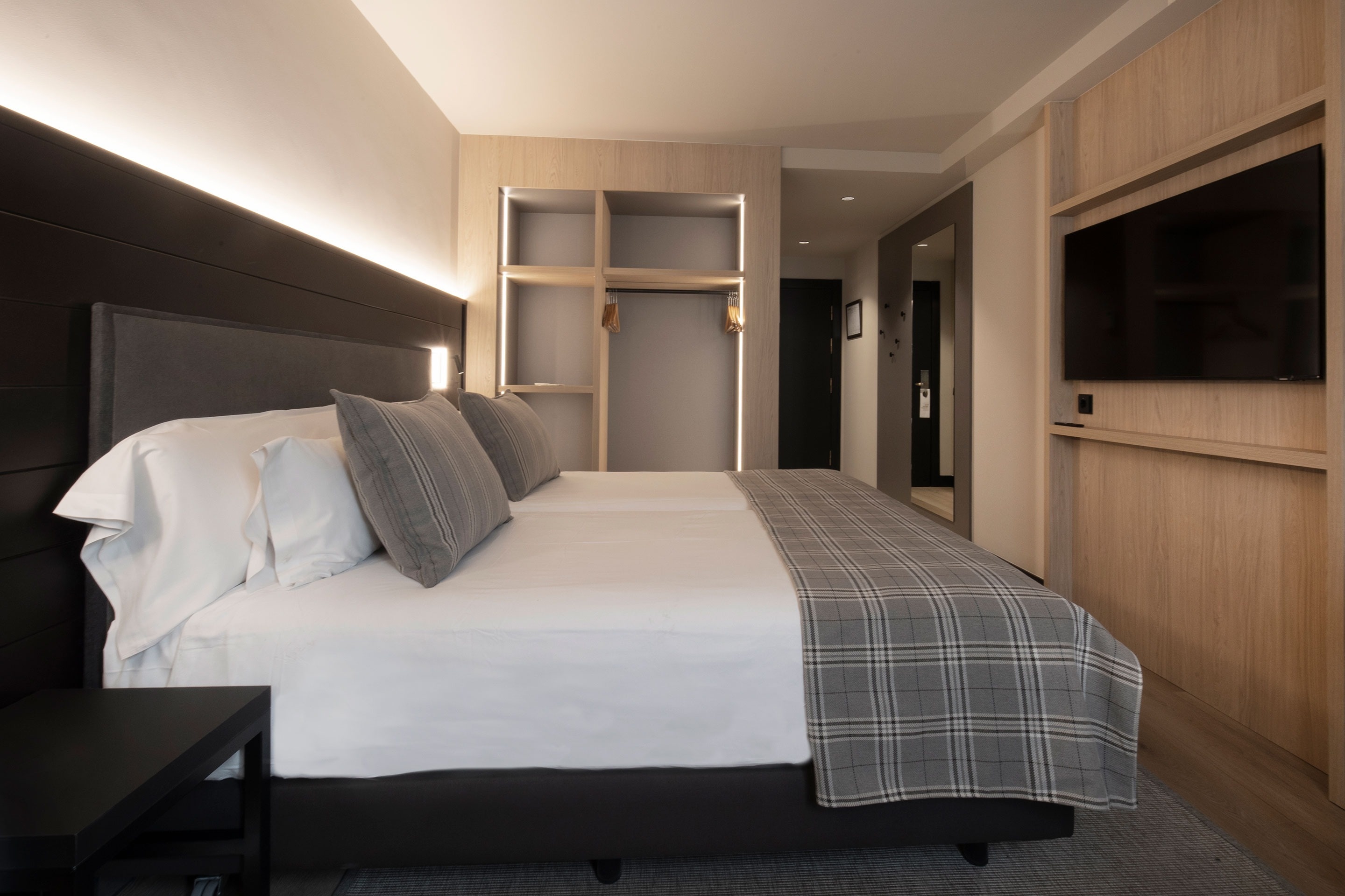 a hotel room with two beds and a flat screen tv