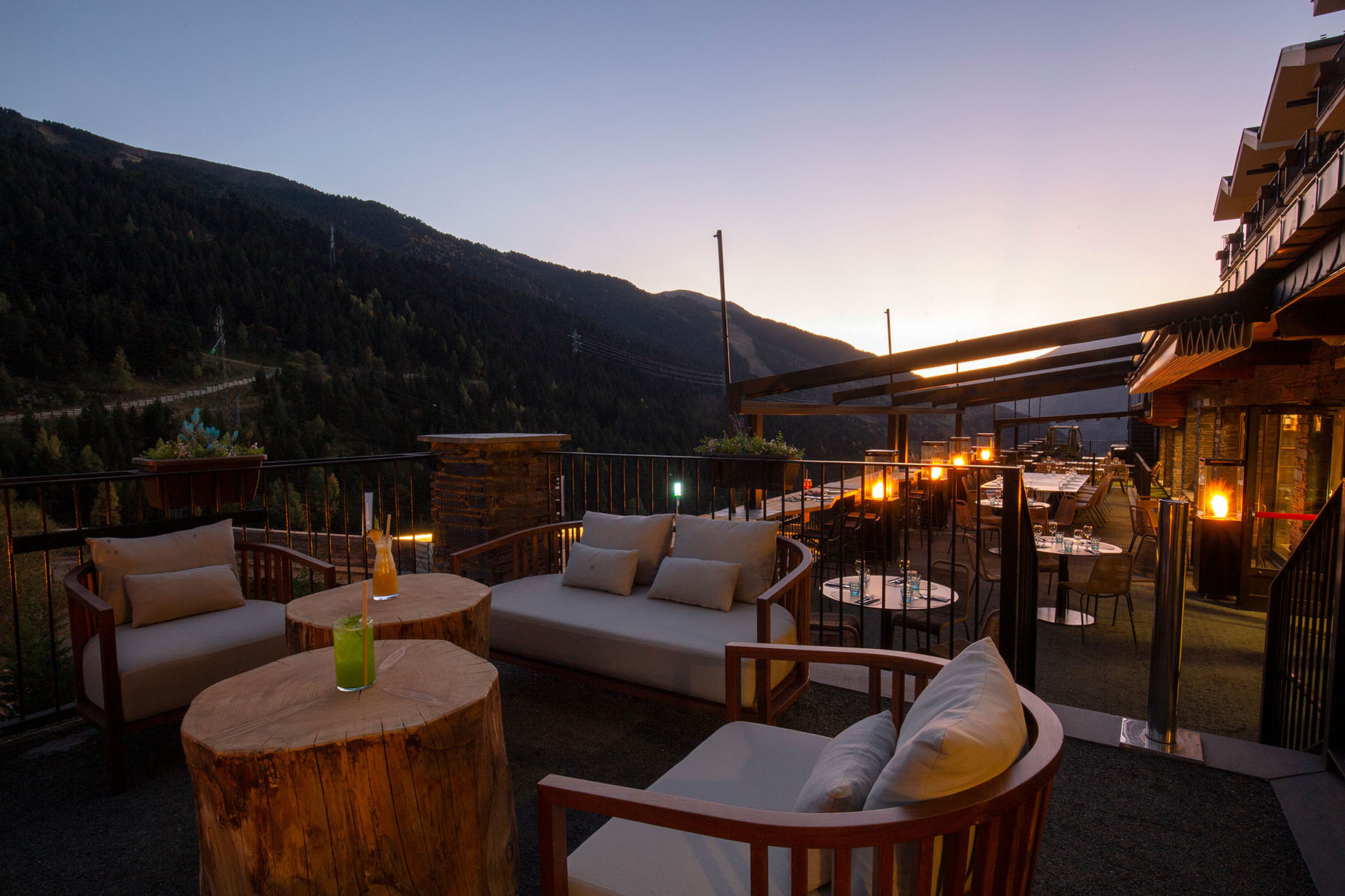 Terraza de NEXTA: Corporativa con vista a la montaña al atardecer, mesas y sofás.