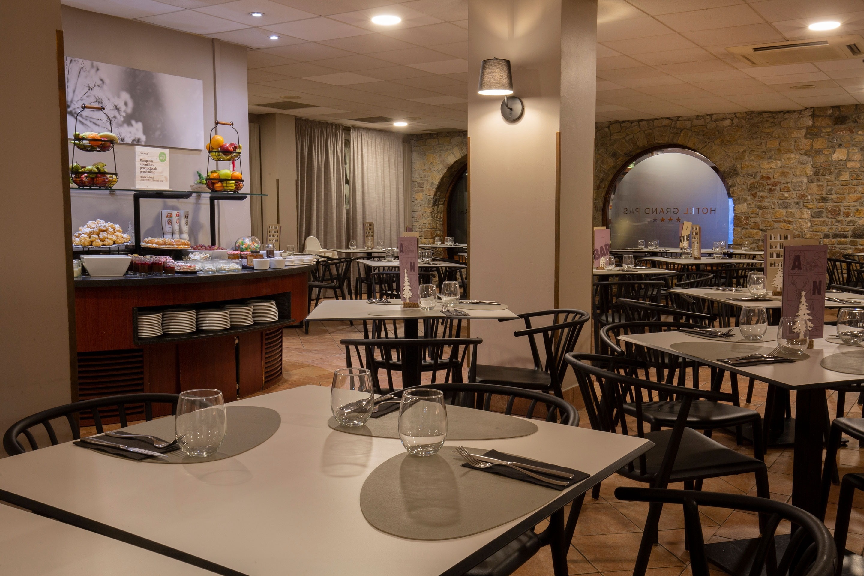 une salle à manger avec des tables et des chaises et un mur en pierre