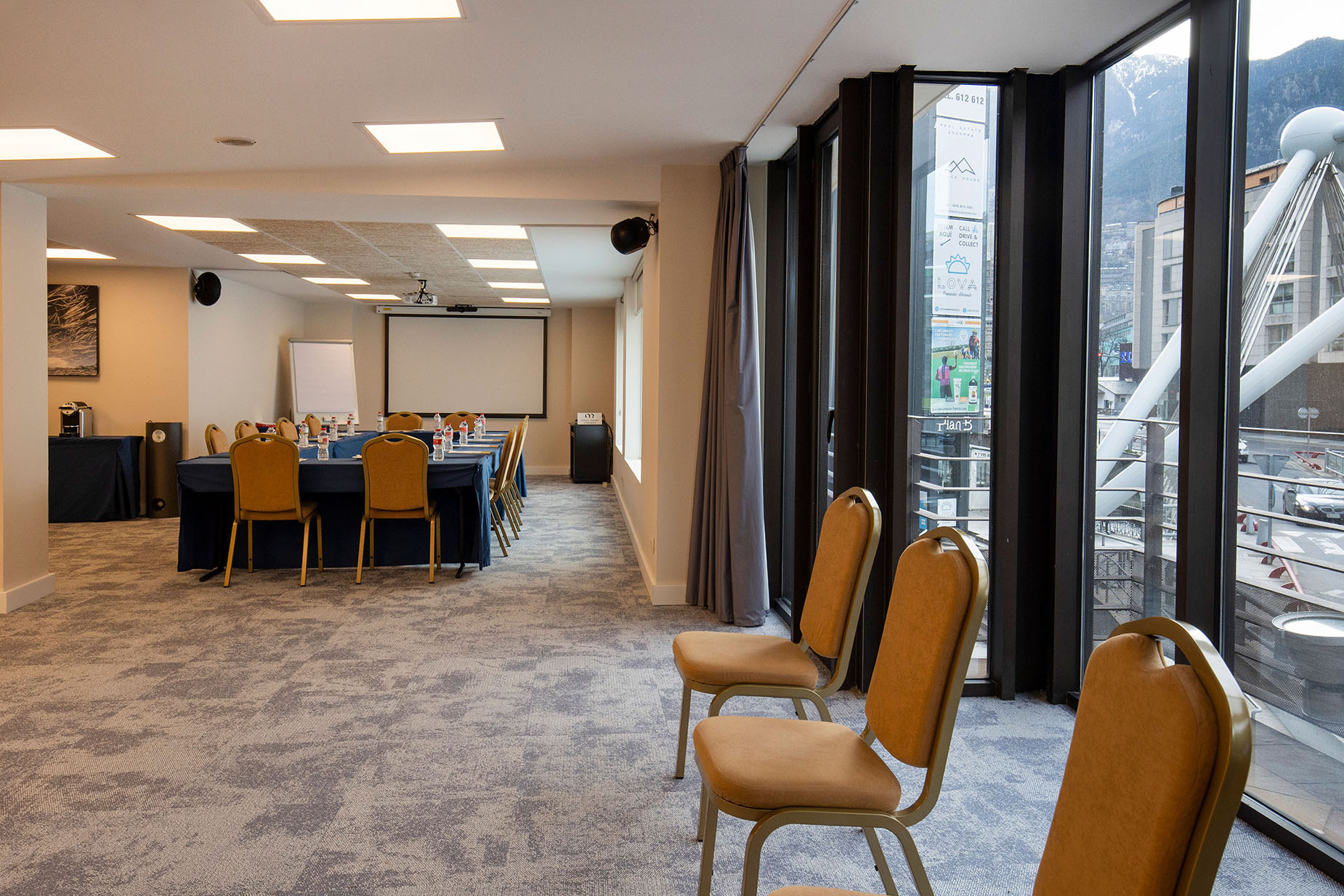 NEXTA: Corporativa: sala de conferències lluminosa amb taula llarga i cadires, vistes a la ciutat i muntanyes.