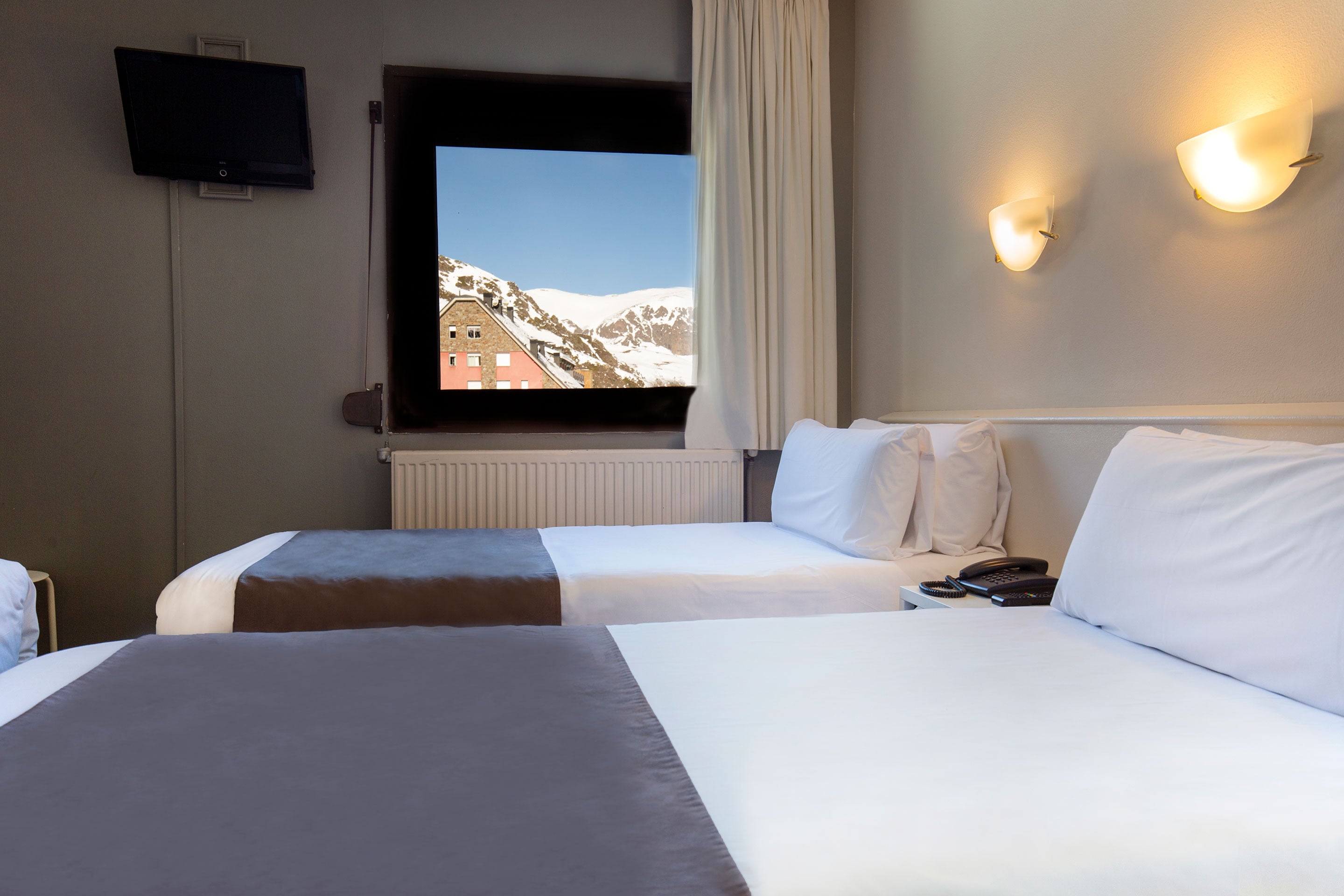 Habitación triple en Hotel Camel·lot | Nexta | Andorra. Camas cómodas, luces de pared y diseño moderno. Reserva oficial.