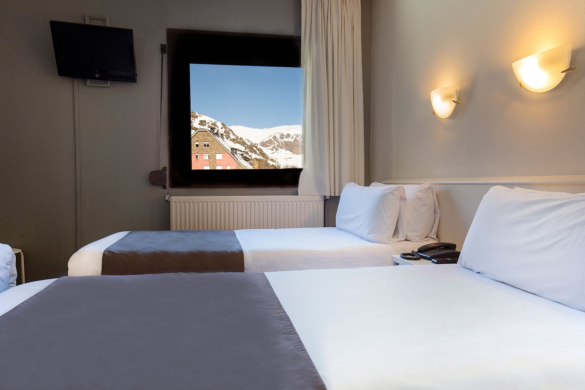 Habitación triple en Hotel Camel·lot | Nexta | Andorra. Camas cómodas, luces de pared y diseño moderno. Reserva oficial.