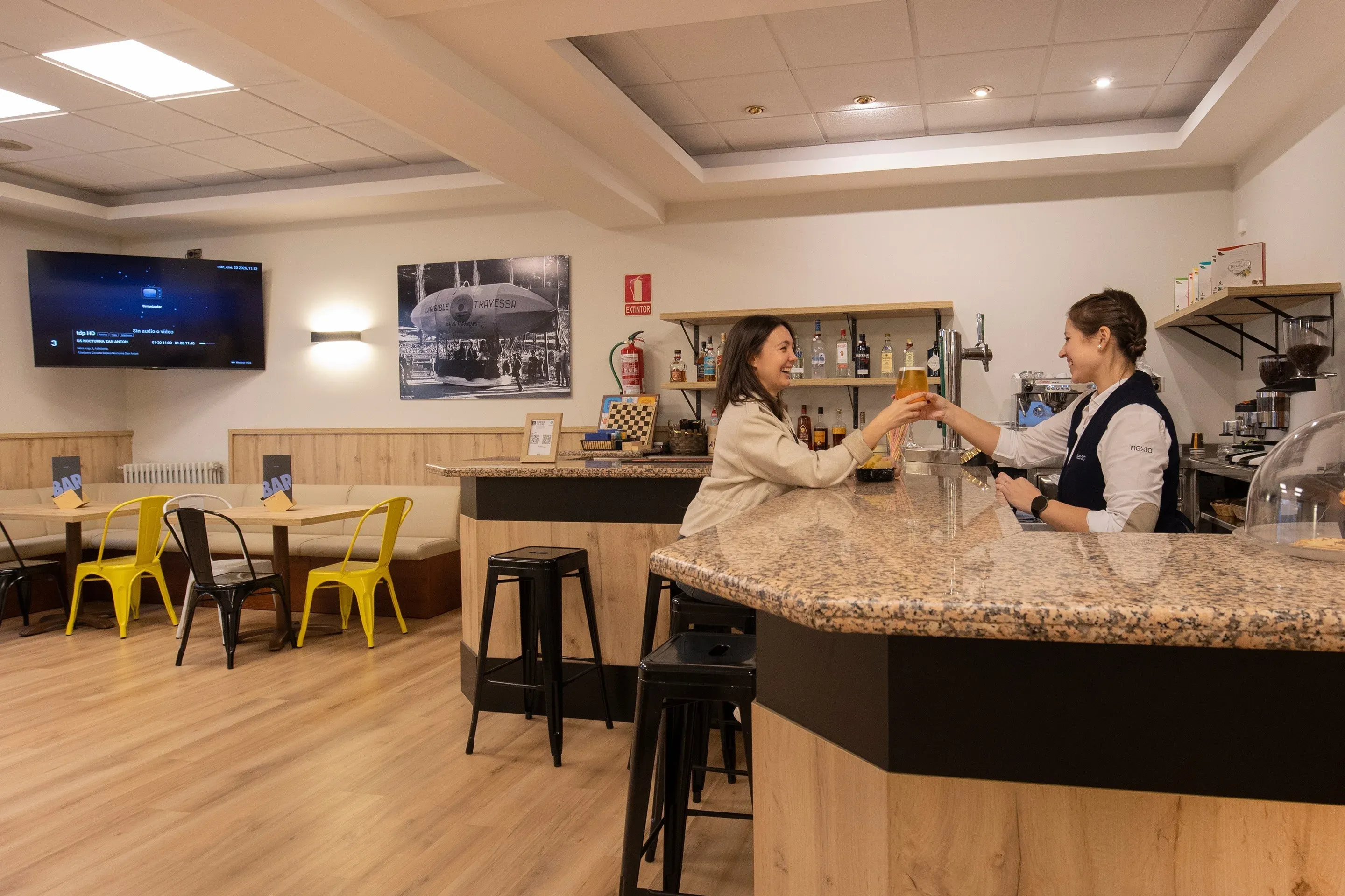 NEXTA: Corporate bar with patrons and a bartender serving drinks.