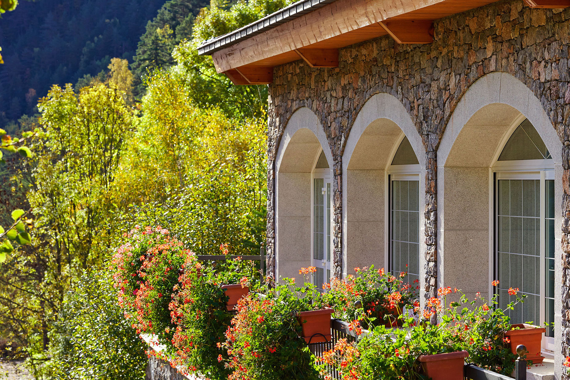 Fachada deNEXTA: Corporativa hotel con arcos, ventanas y balcón con flores.