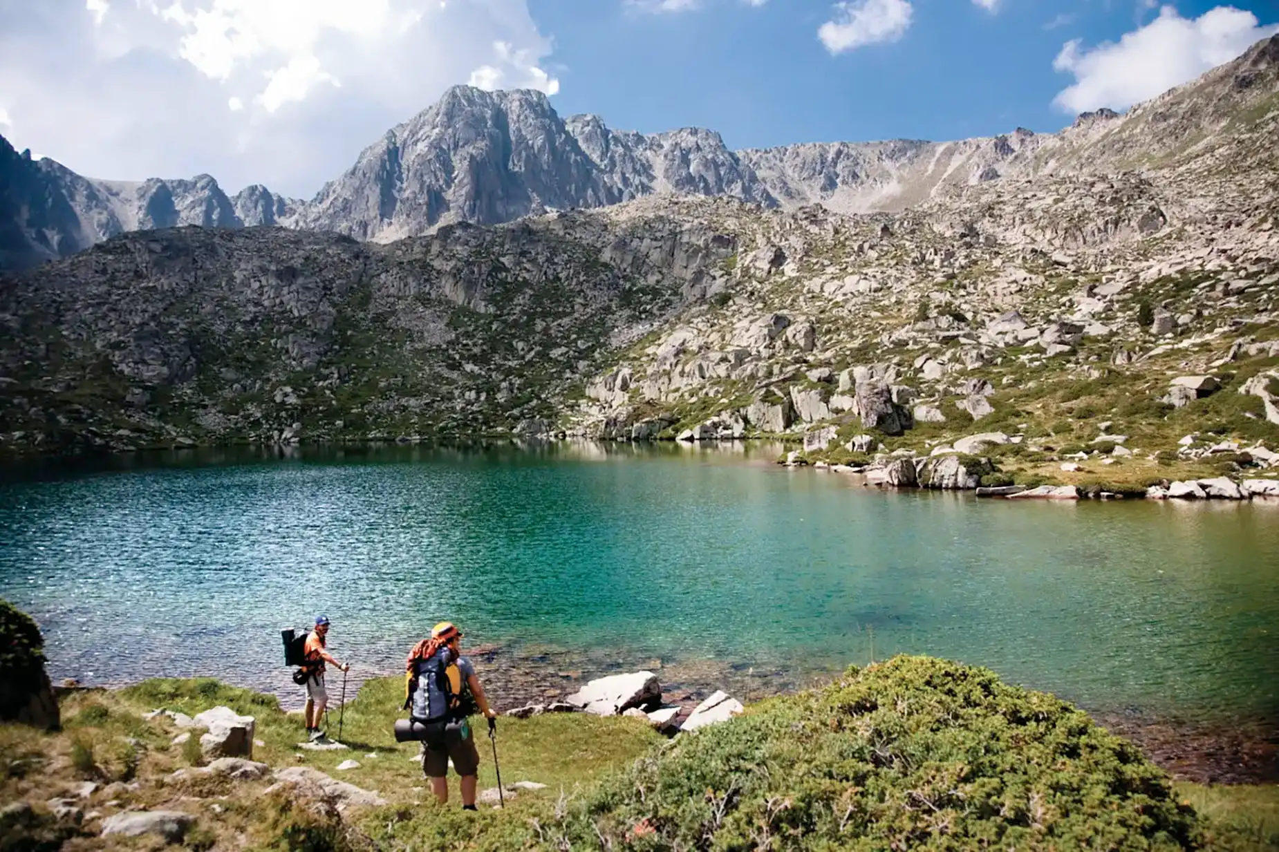 Motel Nexta a la muntanya amb llac de turquesa i excursionistes.