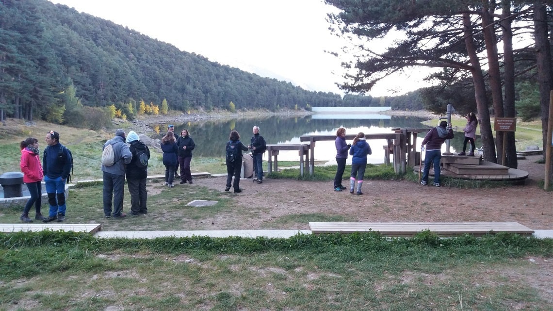 a group of people are standing in front of a lake