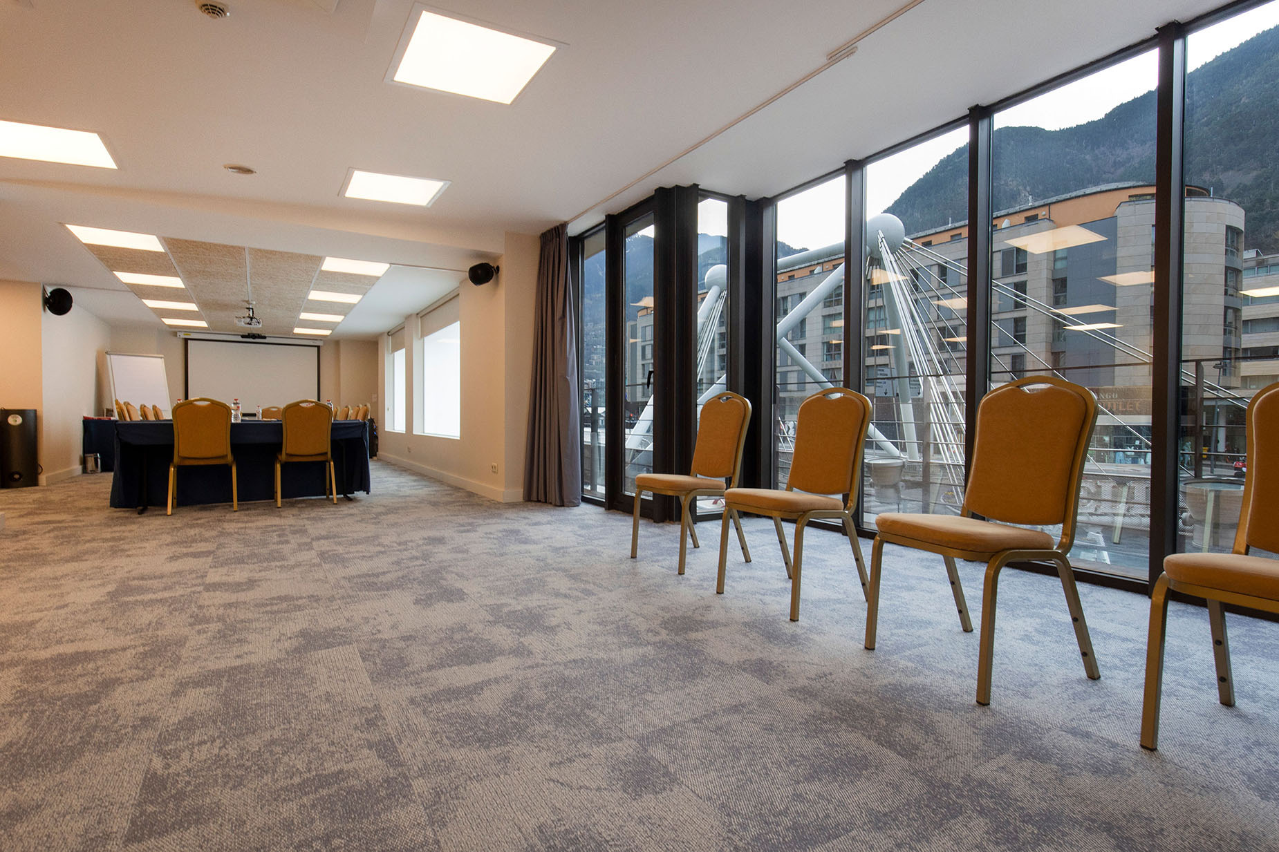 Sala de conferències lluminosa amb taula, cadires i vista a la muntanya. Espai ideal per a NEXTA: Corporativa.