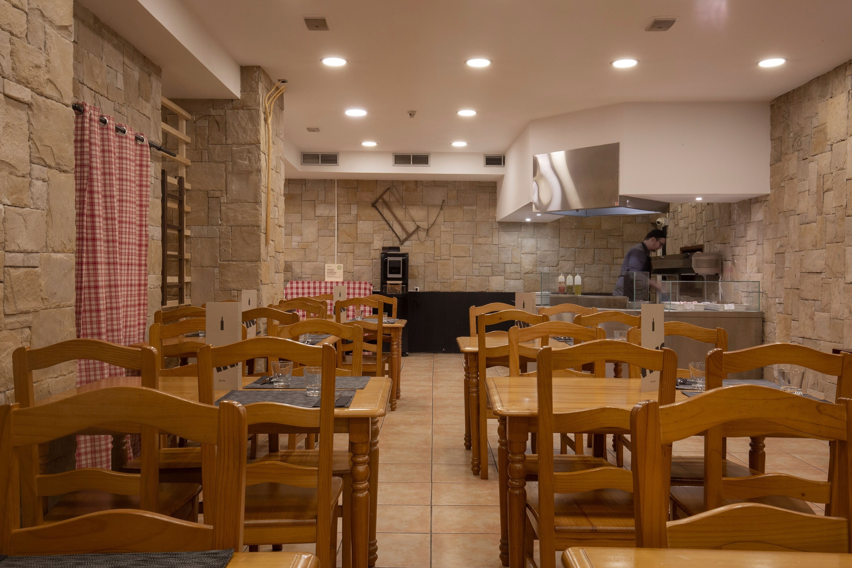 a restaurant with wooden tables and chairs and a man preparing food