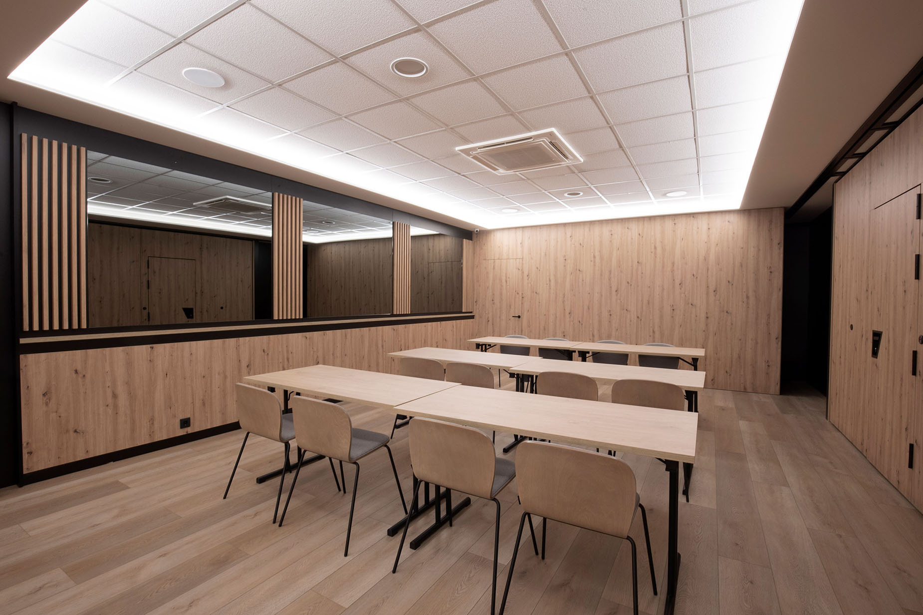 Modern meeting room with light wood accents, tables, chairs, and mirror NEXTA: Corporativa.