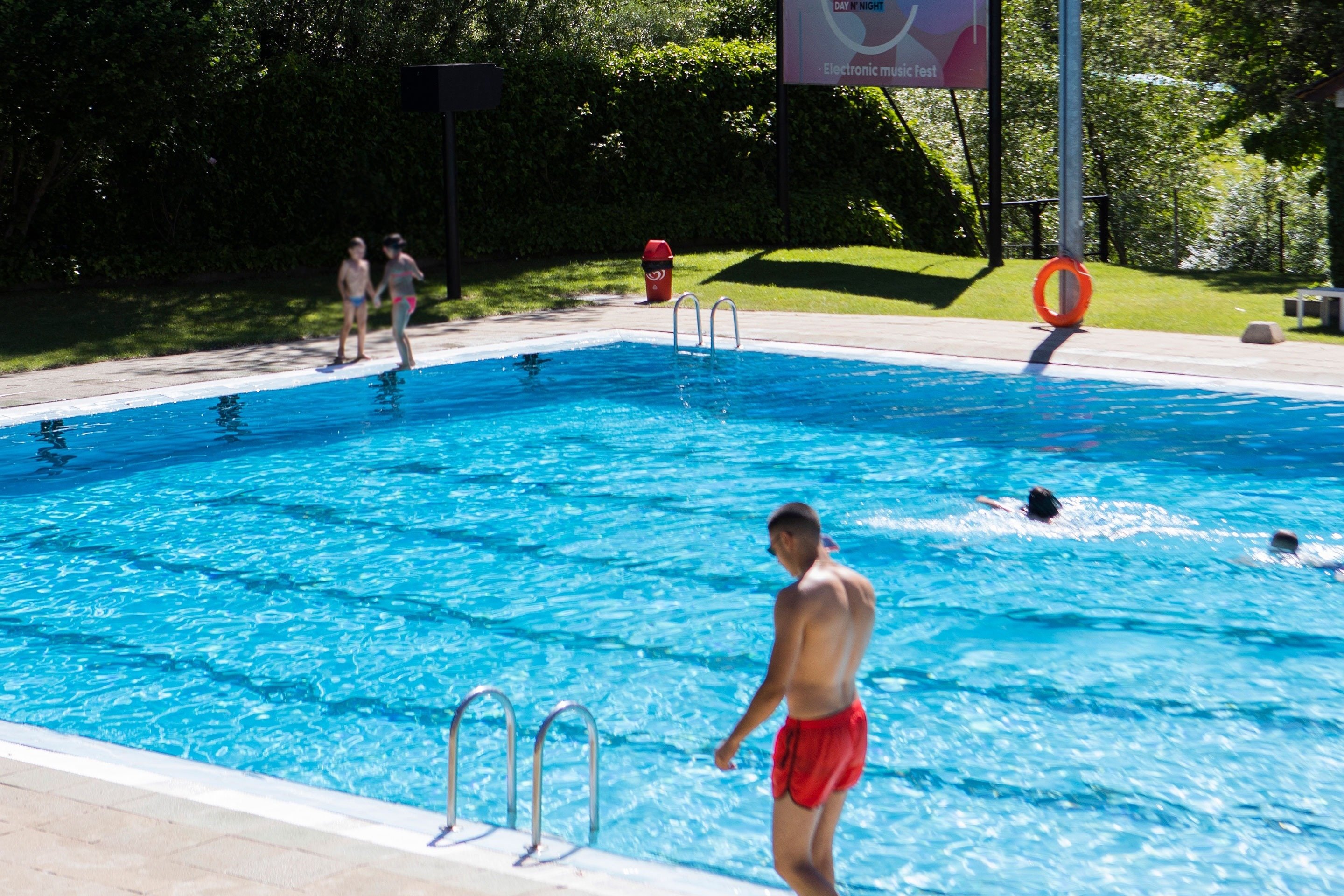 un homme se tient à l' extérieur d' une piscine avec un panneau à côté qui dit electronic music fest