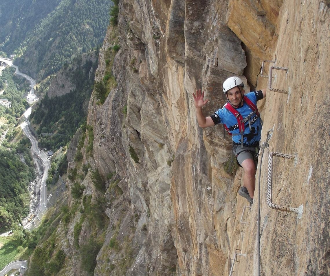 un hombre con una camisa azul y un casco blanco está escalando una pared de roca
