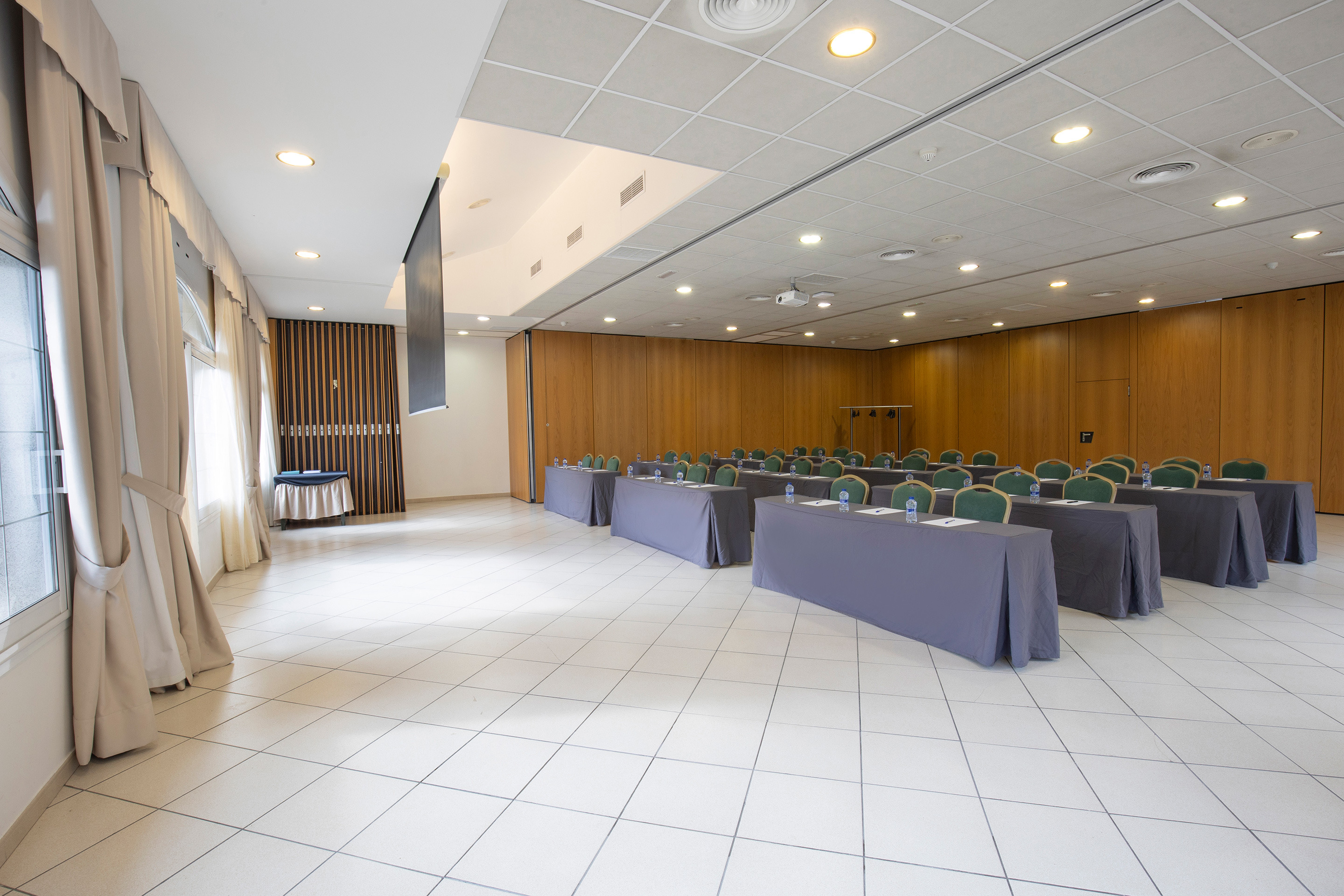 Sala de reuniones con mesas vestidas y sillas verdes para eventos enNEXTA: Corporativa.
