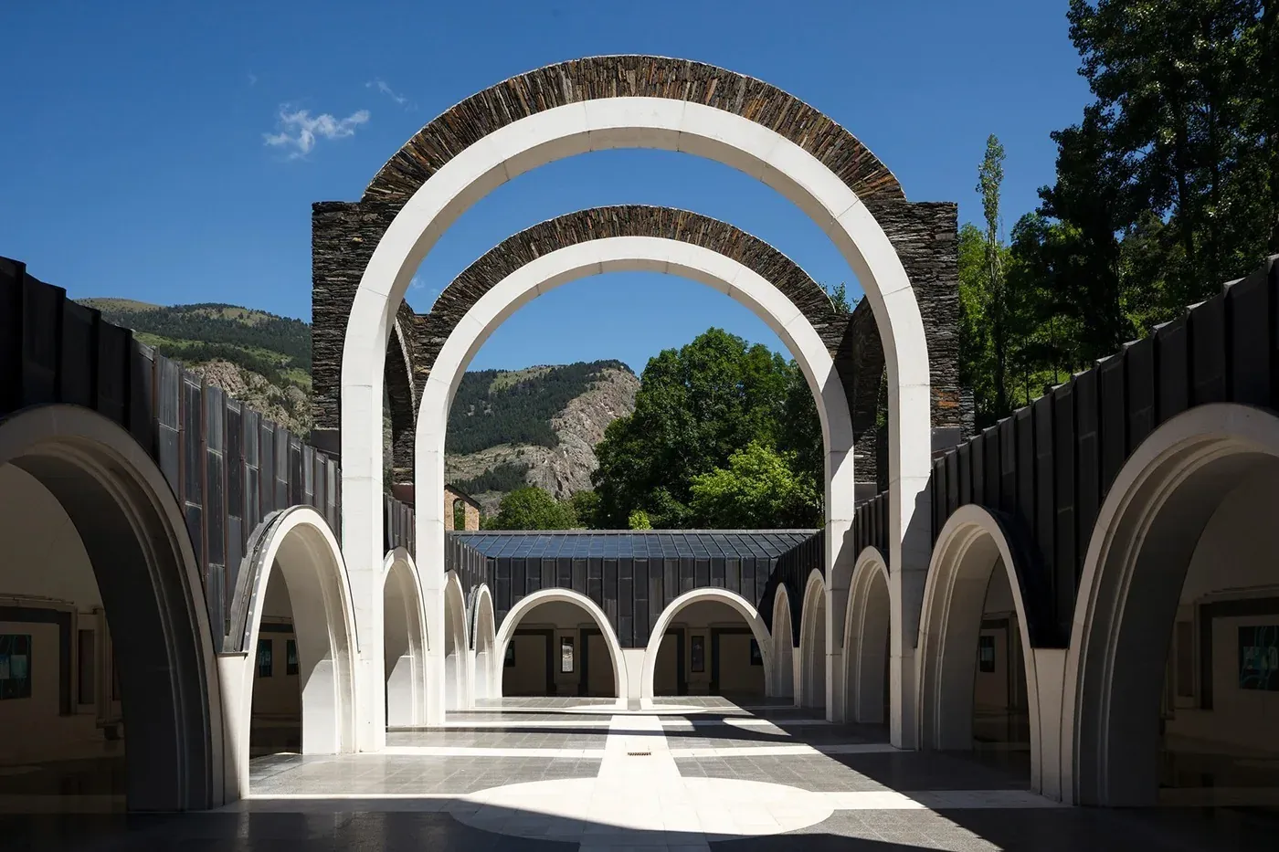 Arches blanches et pierre : extérieur NEXTA: Corporativa. Montagnes vertes.