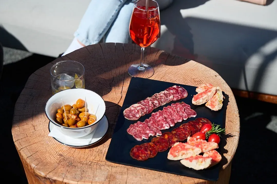 NEXTA Corporate Aperitif: Charcuterie, olives, and cocktail on terrace.