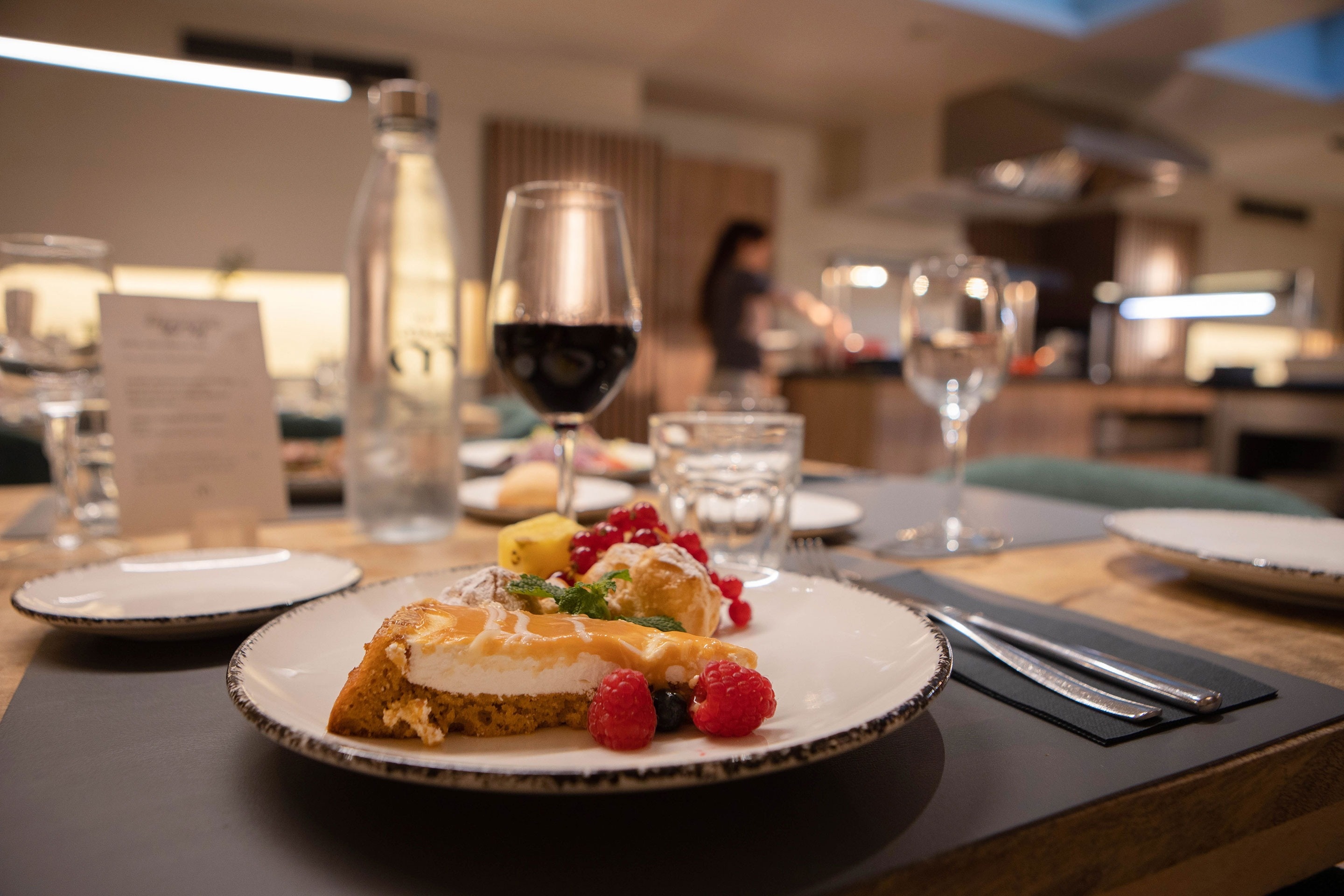 un plato de postre con frambuesas y un vaso de vino