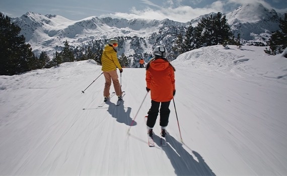 un home i una menina esquían en una pista nevada