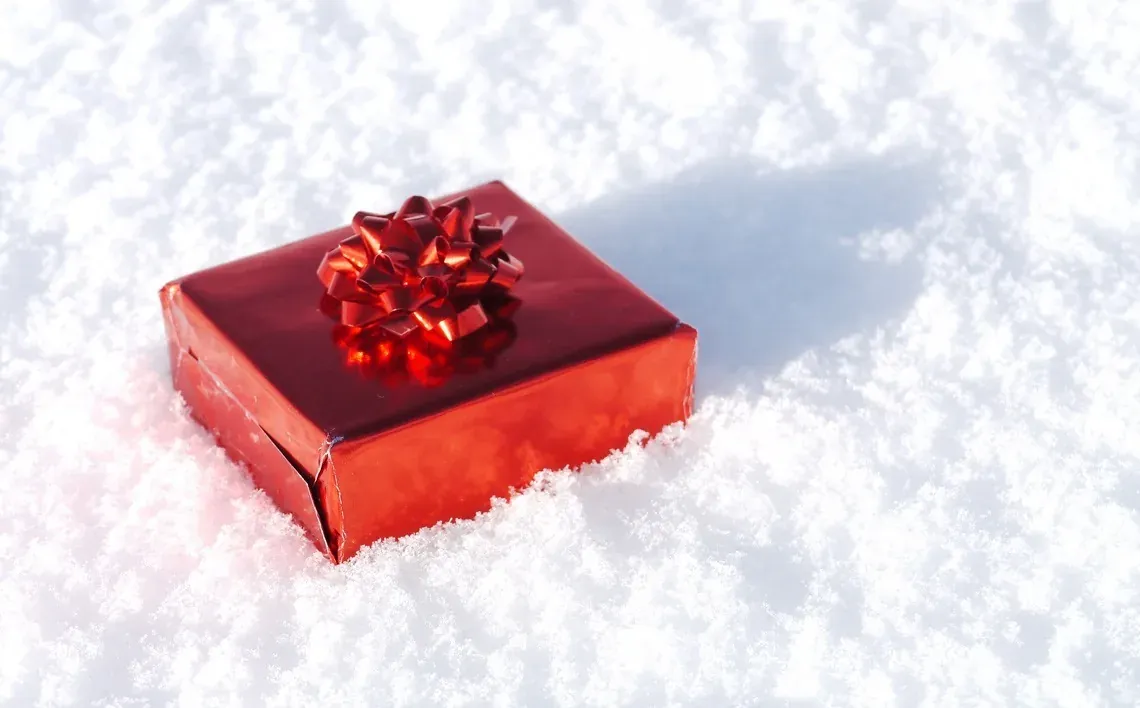 Cadeau rouge brillant sur la neige, idéal pour les événements NEXTA: Corporativa.