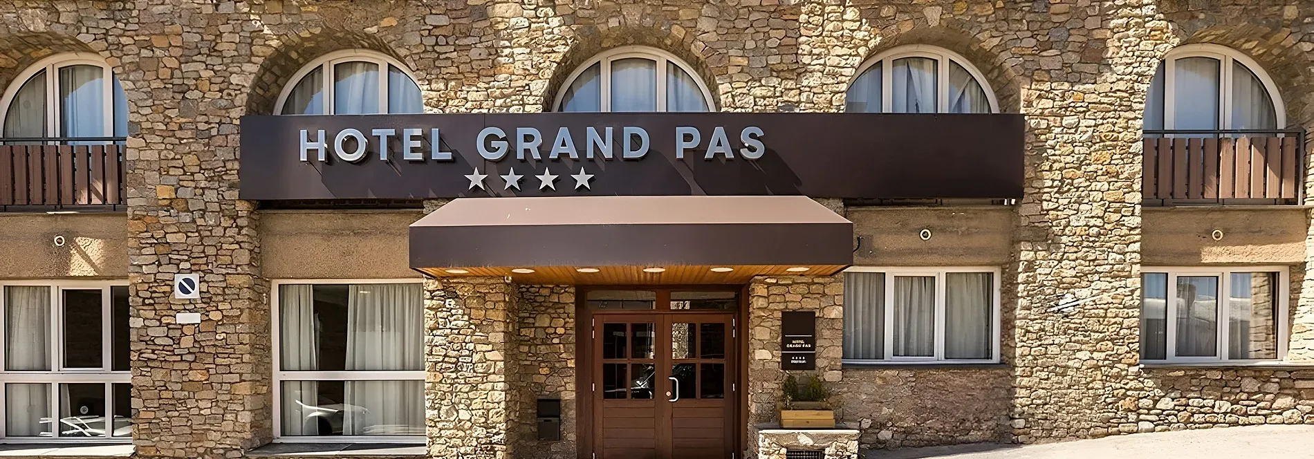 Exterior del Hotel Grand Pas, fachada de piedra y entrada principal. Hotel de esquí en la montaña.