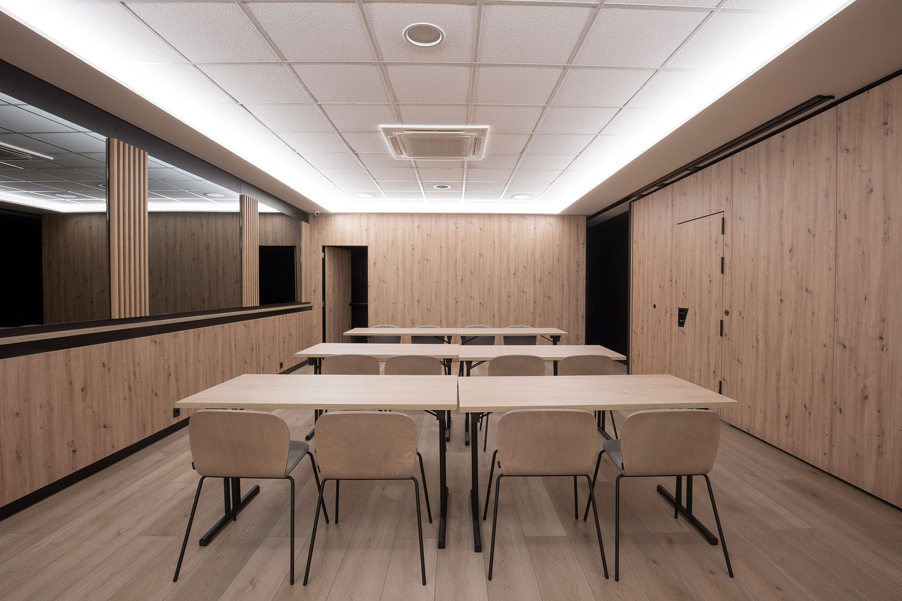 Modern meeting room with light wood paneling and tables, ideal for NEXTA: Corporativa.