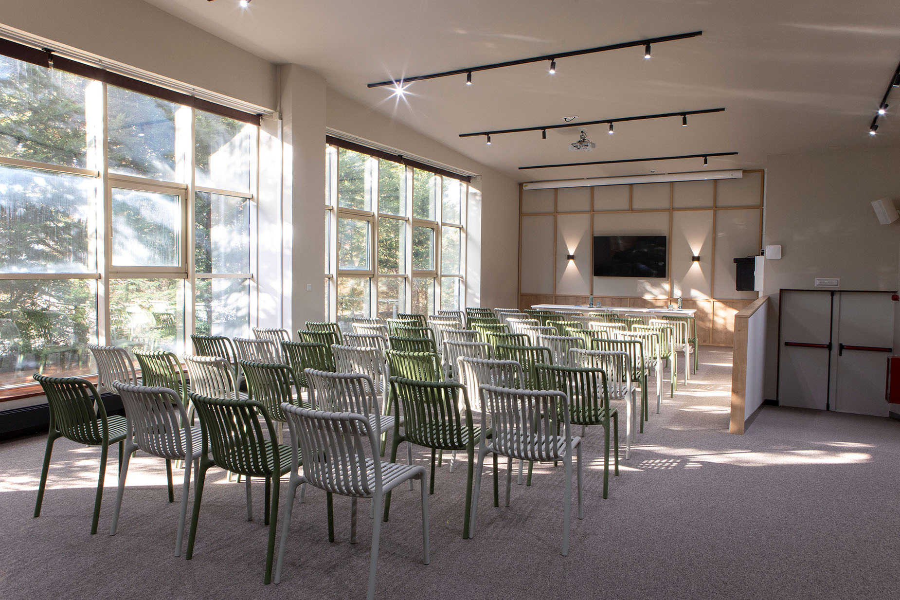 Salón de eventos moderno con sillas verdes y blancas, ideal para NEXTA: Corporativa.