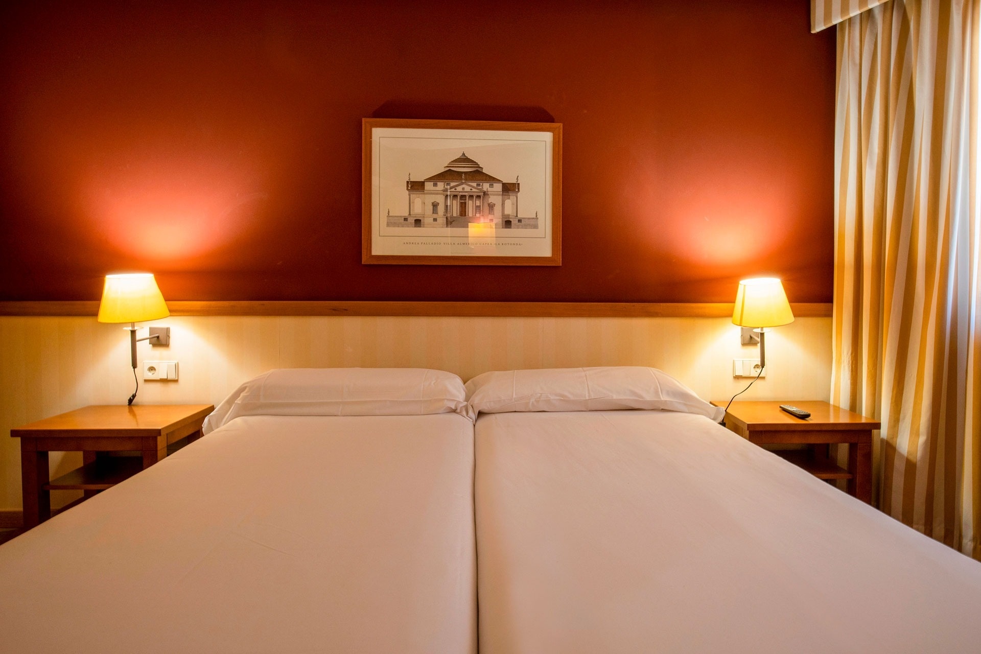 a hotel room with two beds and a picture of a building on the wall