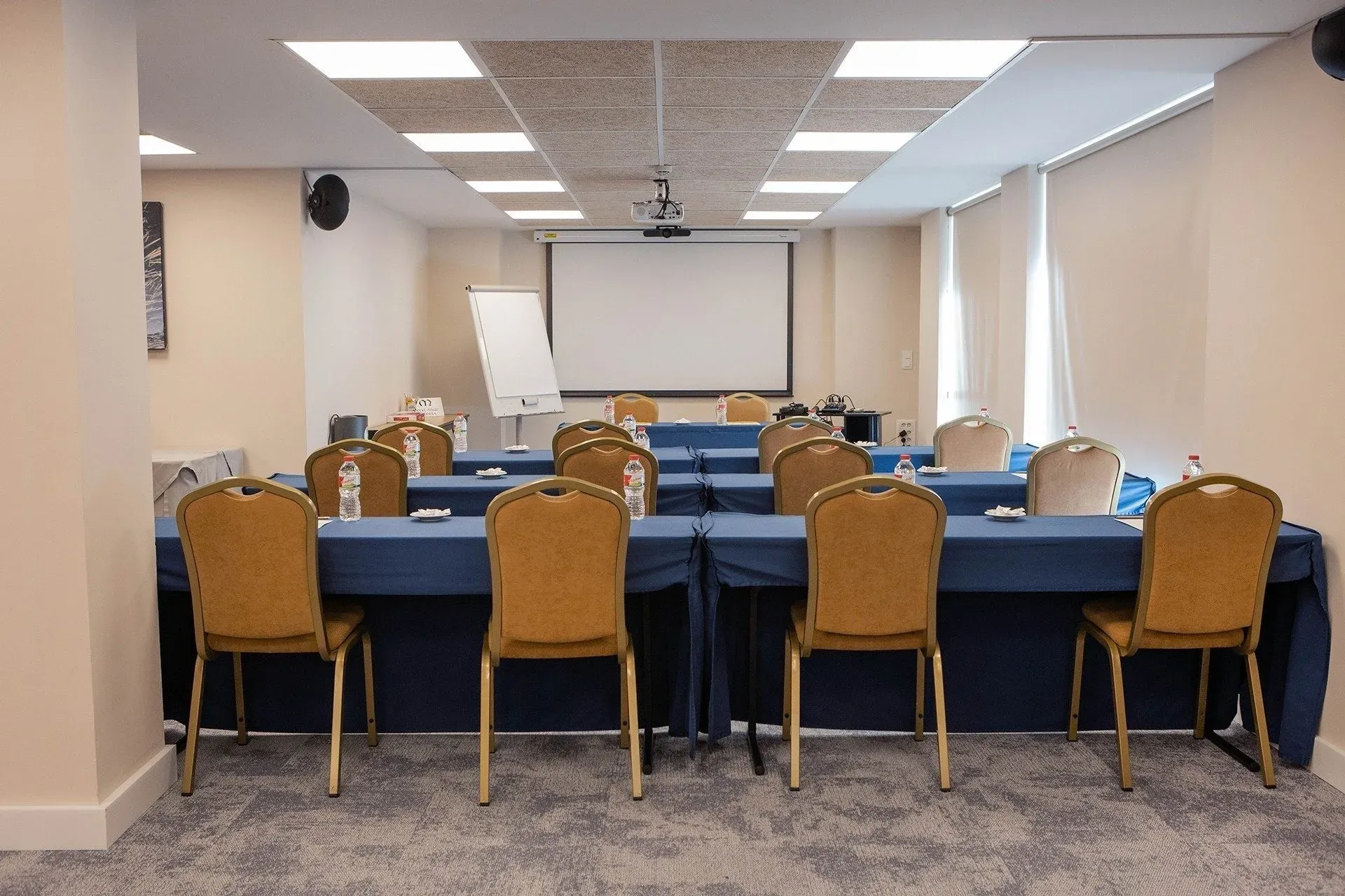 Salón de eventos NEXTA: Corporativa, sillas doradas y mesas azules.