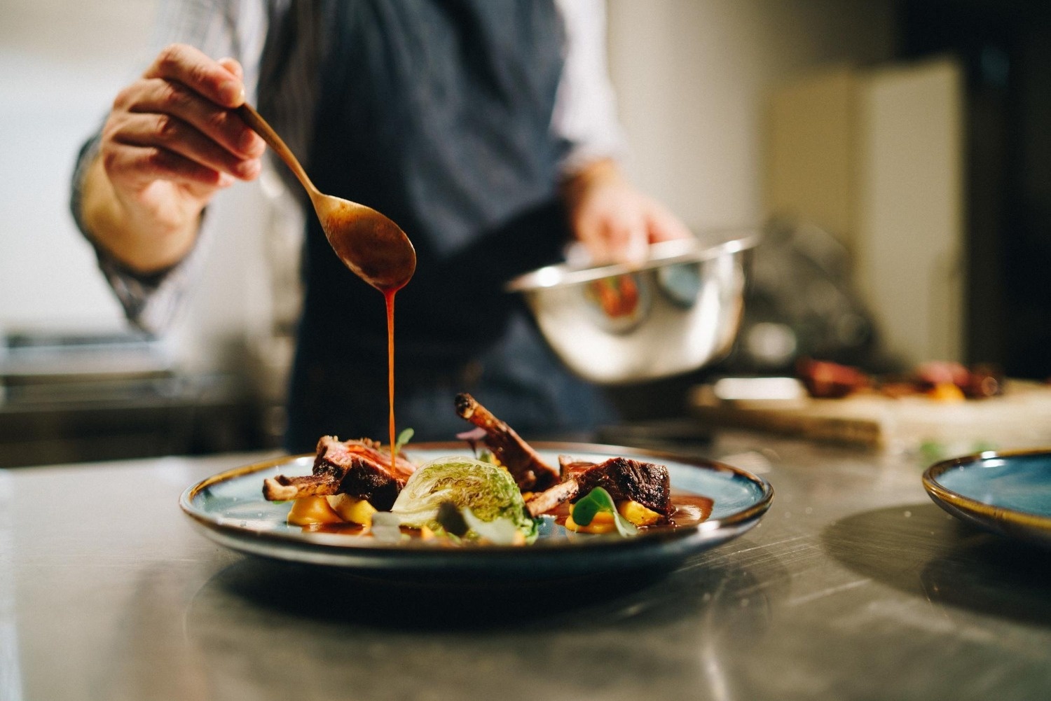 un chef vierte salsa sobre un plato de comida