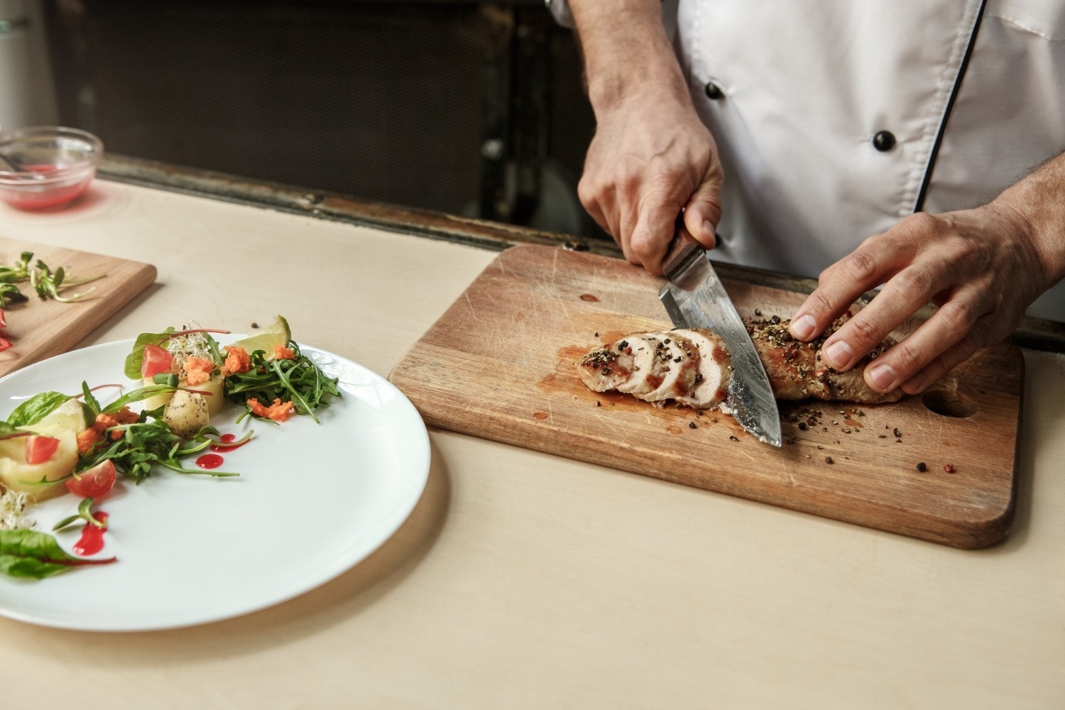 un chef corta un trozo de carne en una tabla de cortar de madera