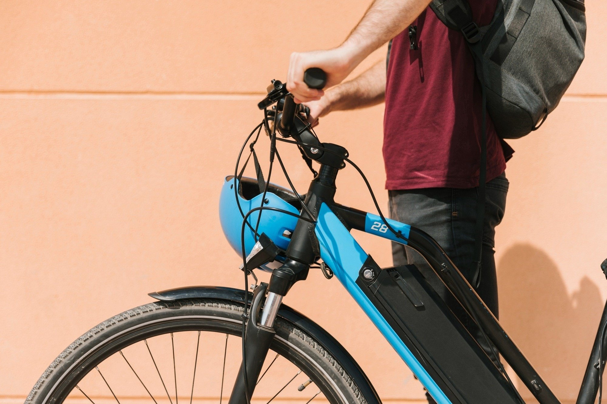 un hombre sostiene el manillar de una bicicleta azul con la palabra 28 en la parte superior