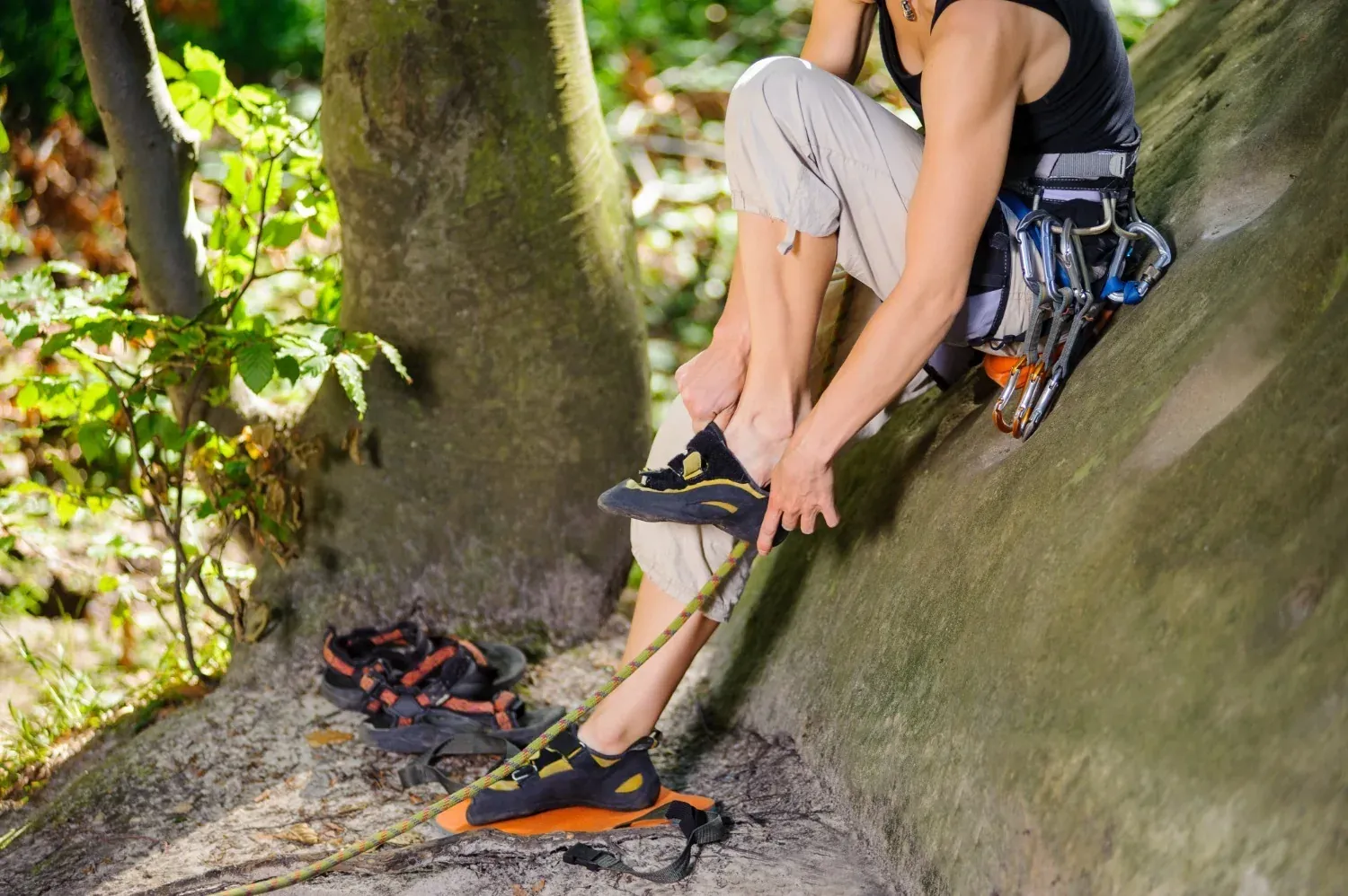 NEXTA: Corporativa. Climber putting on climbing shoes near tree.