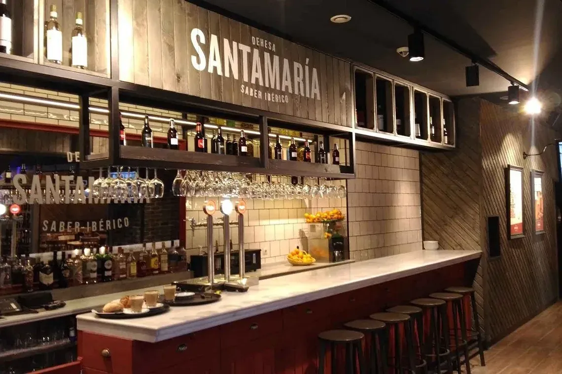 NEXTA: Corporativa hotel bar, featuring bottles, glassware, and stools