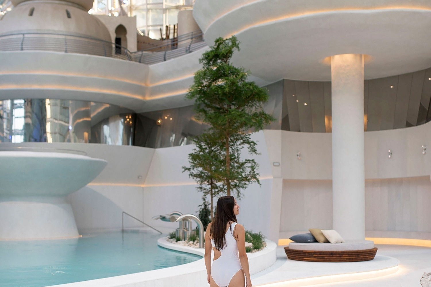 una mujer con traje de baño blanco está parada junto a una piscina