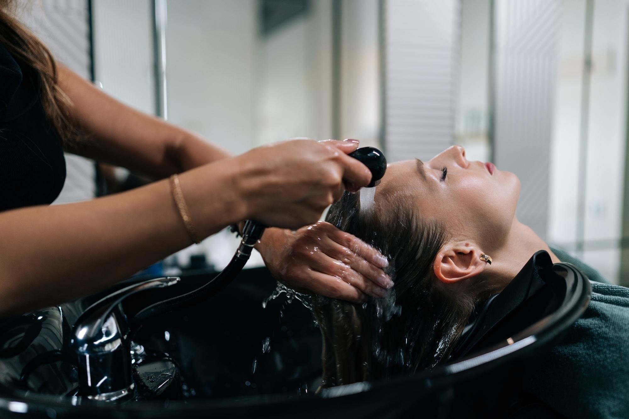 una mujer se lava el cabello en un lavabo en un salón