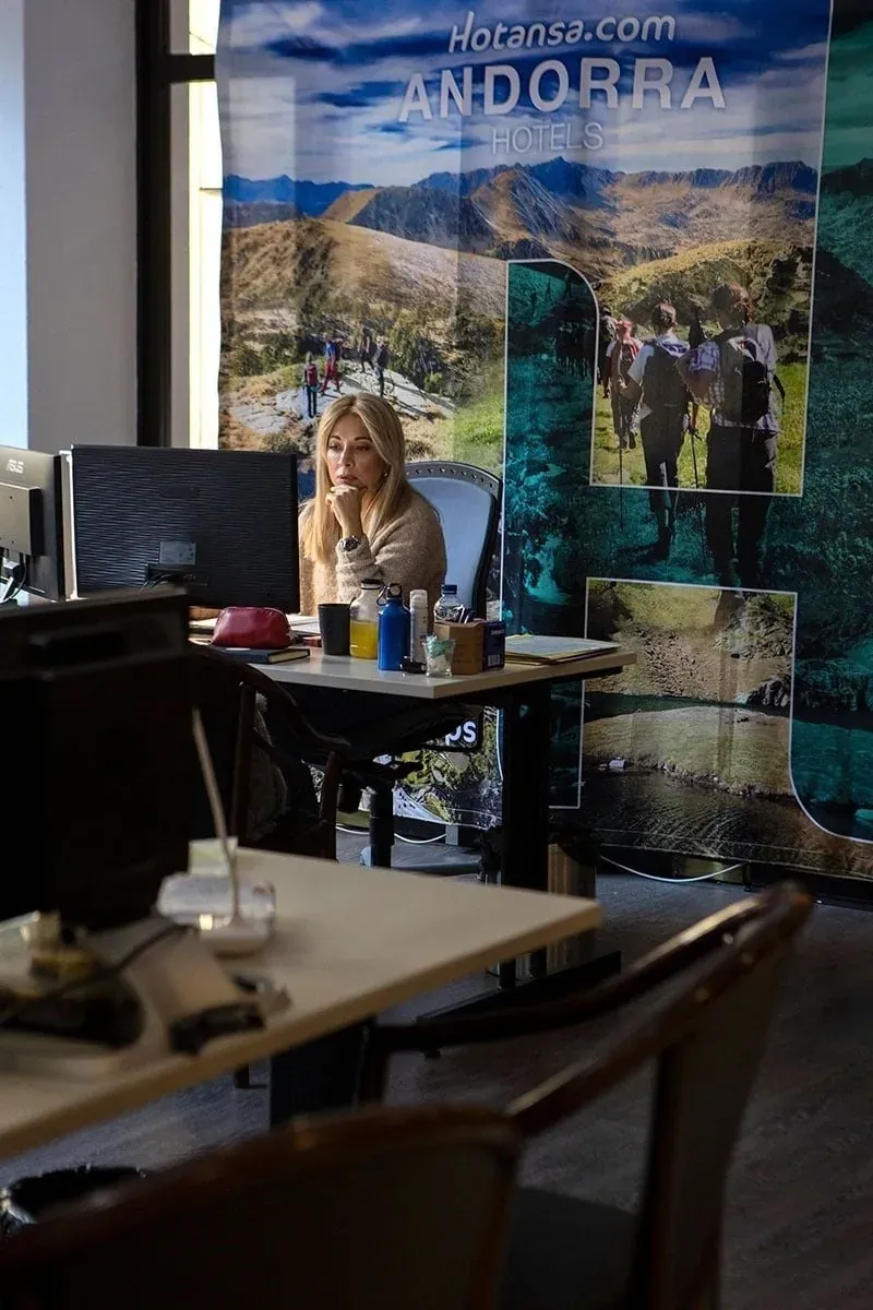 Agente de NEXTA: Corporativa atenta en oficina con fondo promocional de Andorra.