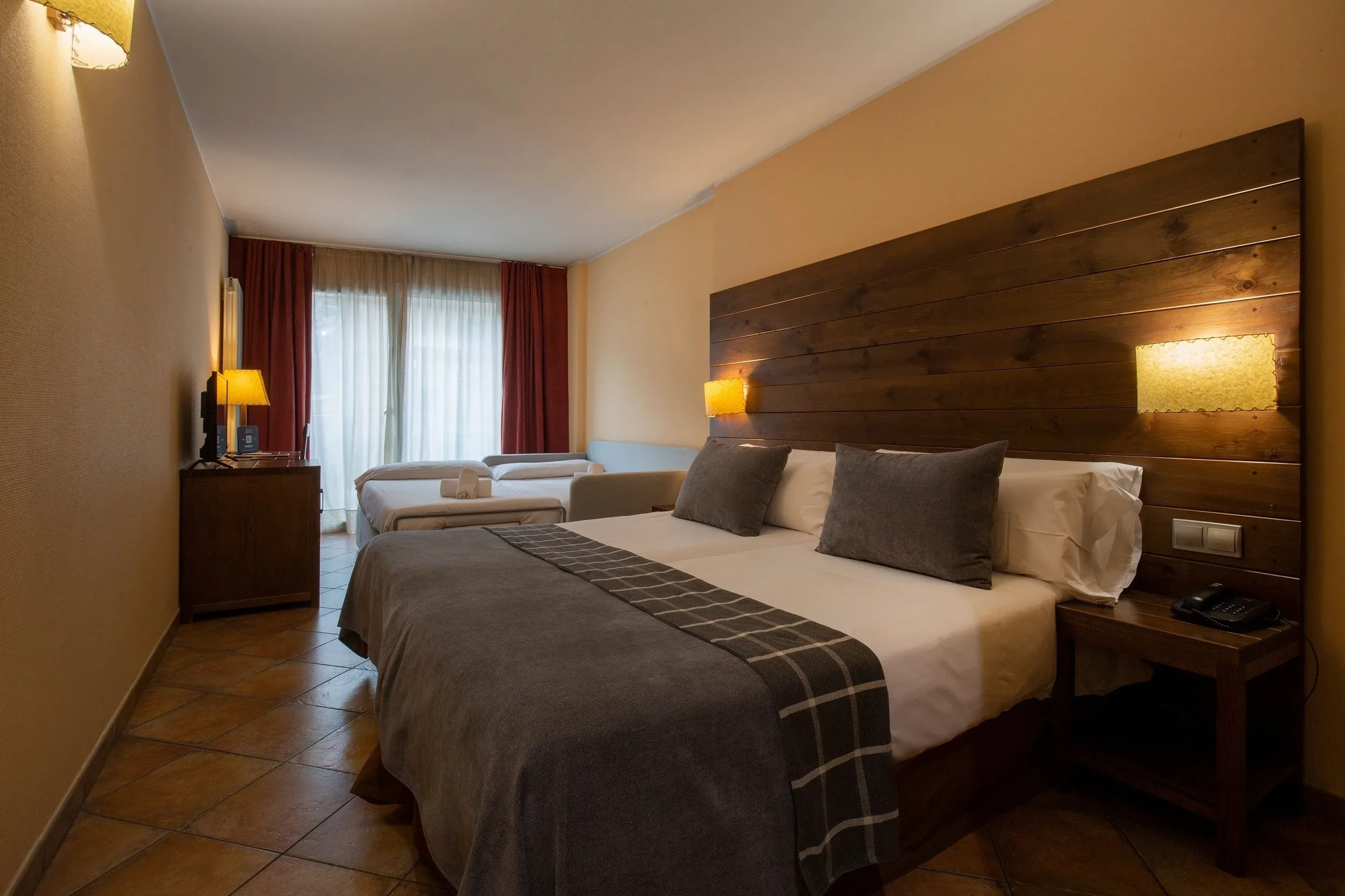 Habitación NEXTA: Corporativa con dos camas, sofá cama y cabecero de madera.