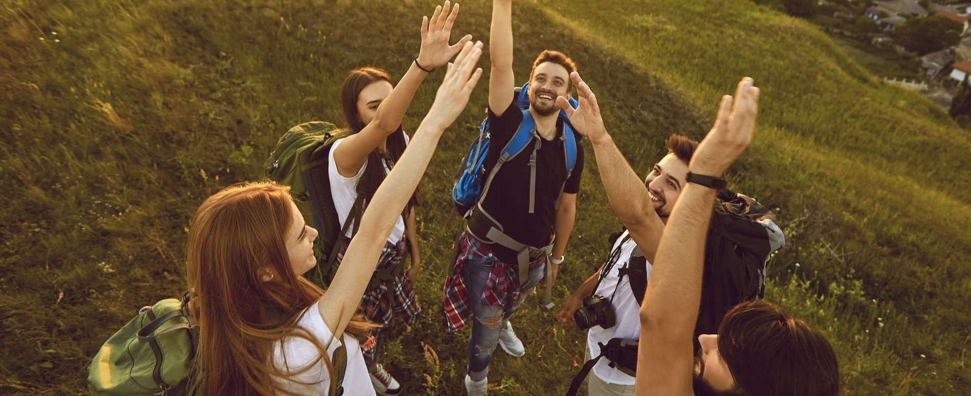 un grupo de jóvenes con mochilas levantan sus manos en el aire