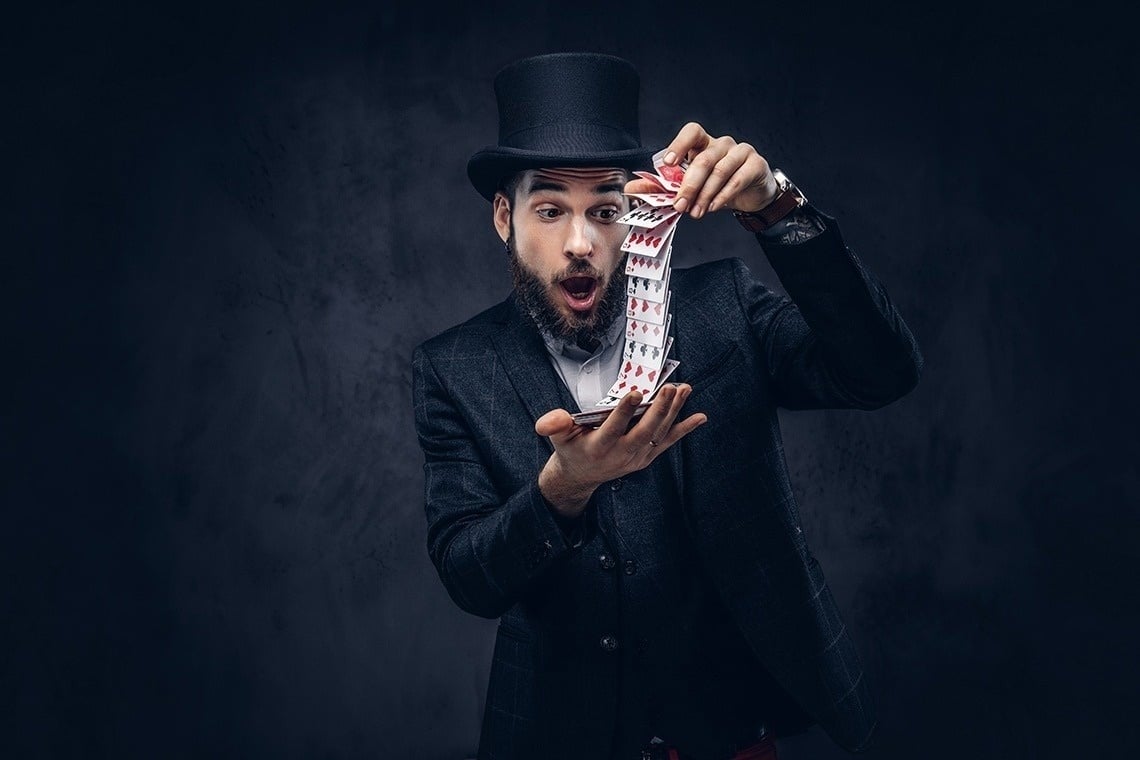 un homme vêtu d' un chapeau haut de forme tient une pile de cartes .
